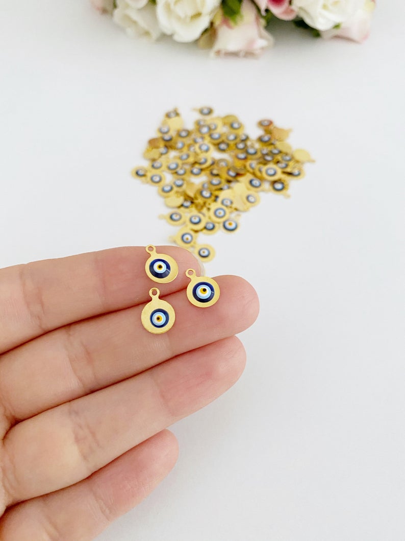 Tiny gold evil eye bead charm on a white background, showcasing its 10mm size and intricate design.