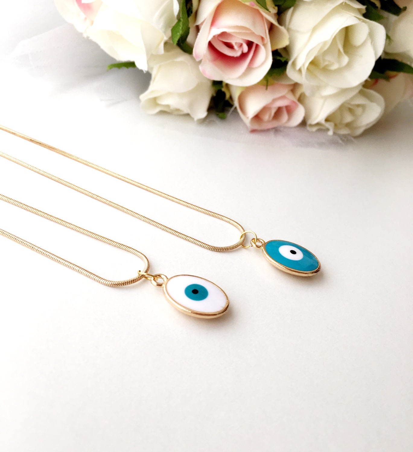 A delicate Tiny Evil Eye Necklace featuring turquoise and white oval beads on a 22K gold plated chain, symbolizing protection and style.
