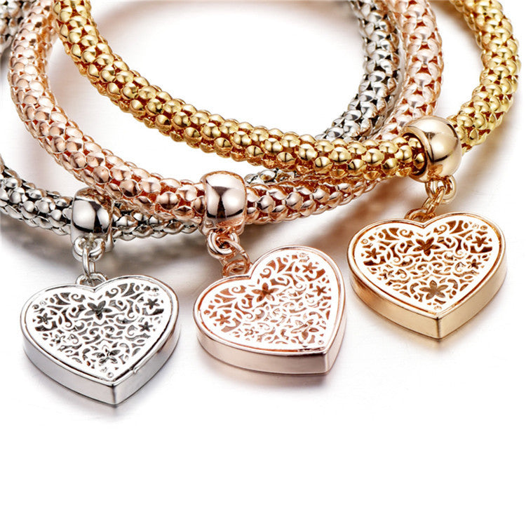 A set of three elegant mesh bracelets featuring filigree heart designs, crafted with 14K gold plating and a stretch-pull clasp.
