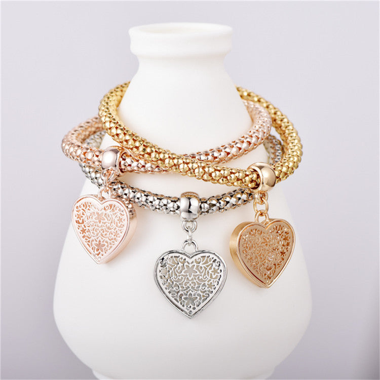 A set of three elegant mesh bracelets featuring filigree heart designs, crafted with 14K gold plating and a stretch-pull clasp.