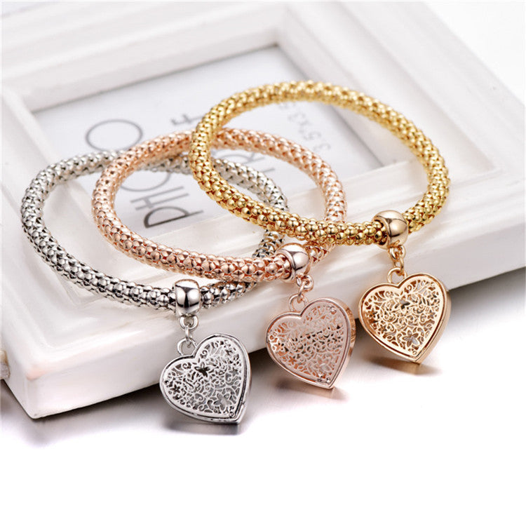 A set of three elegant mesh bracelets featuring filigree heart designs, crafted with 14K gold plating and a stretch-pull clasp.