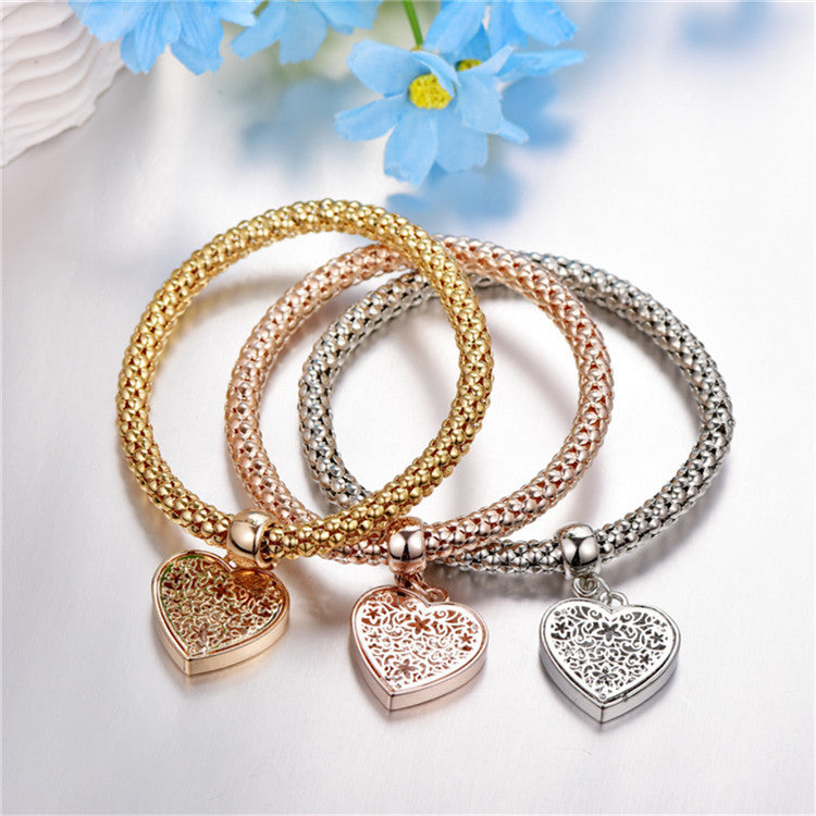 A set of three elegant mesh bracelets featuring filigree heart designs, crafted with 14K gold plating and a stretch-pull clasp.