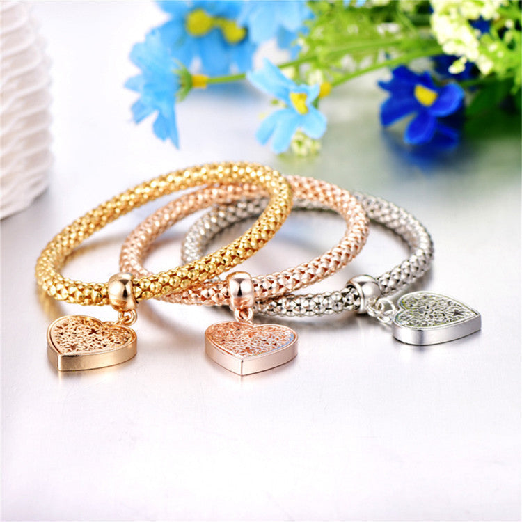 A set of three elegant mesh bracelets featuring filigree heart designs, crafted with 14K gold plating and a stretch-pull clasp.
