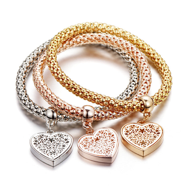 A set of three elegant mesh bracelets featuring filigree heart designs, crafted with 14K gold plating and a stretch-pull clasp.