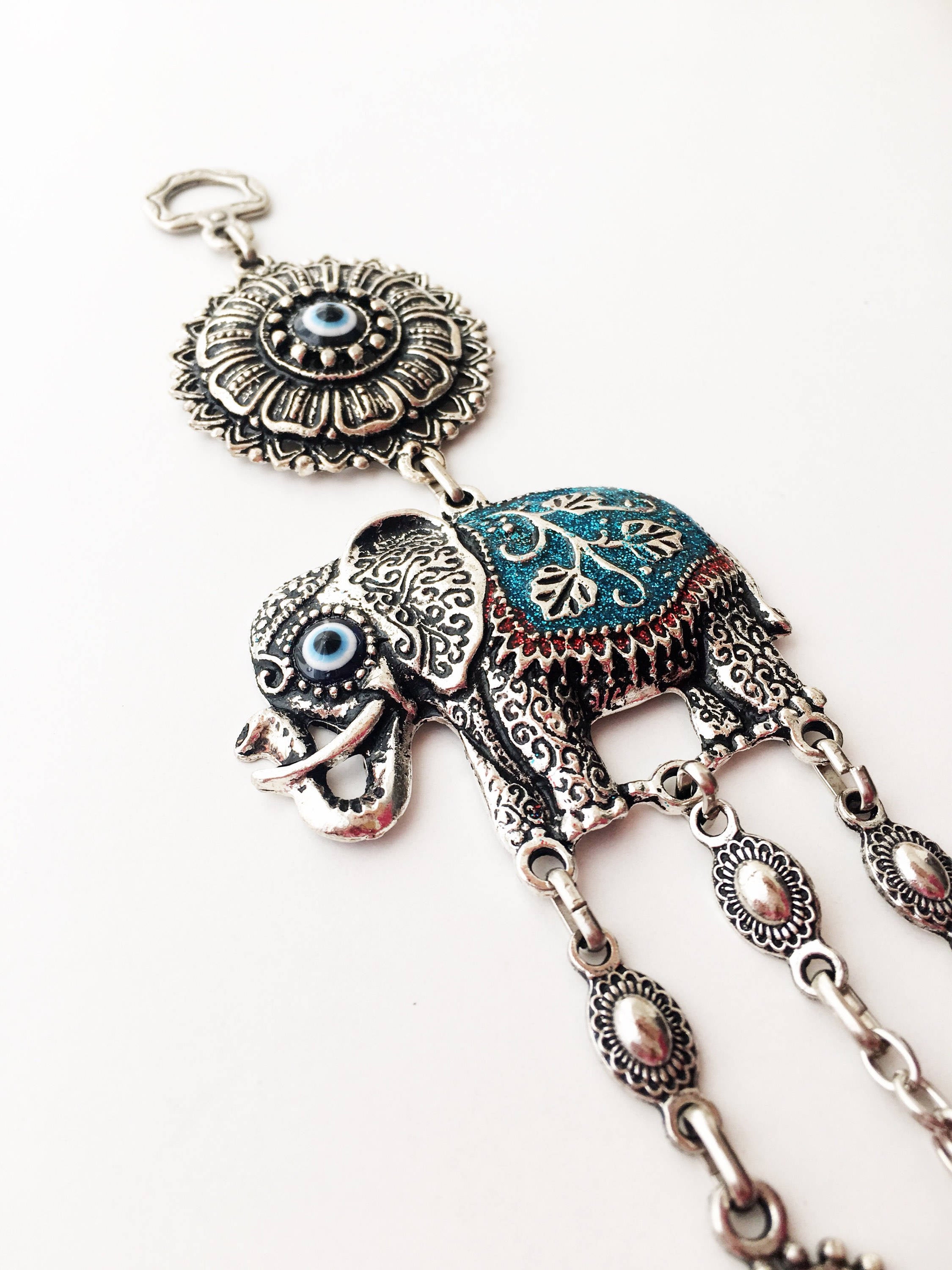 Handmade turquoise elephant wall art featuring an evil eye charm, symbolizing protection and good luck.