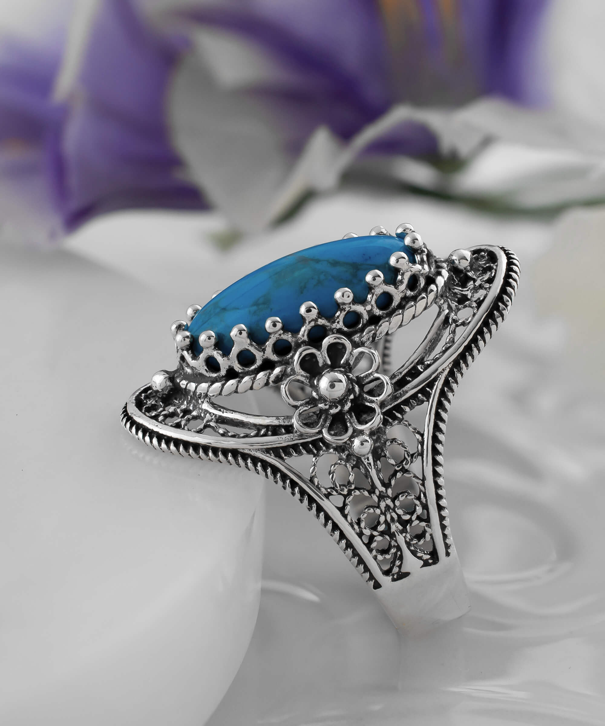 Turquoise gemstone sterling silver filigree ring with daisy accents, showcasing an oval cut turquoise stone and intricate design.