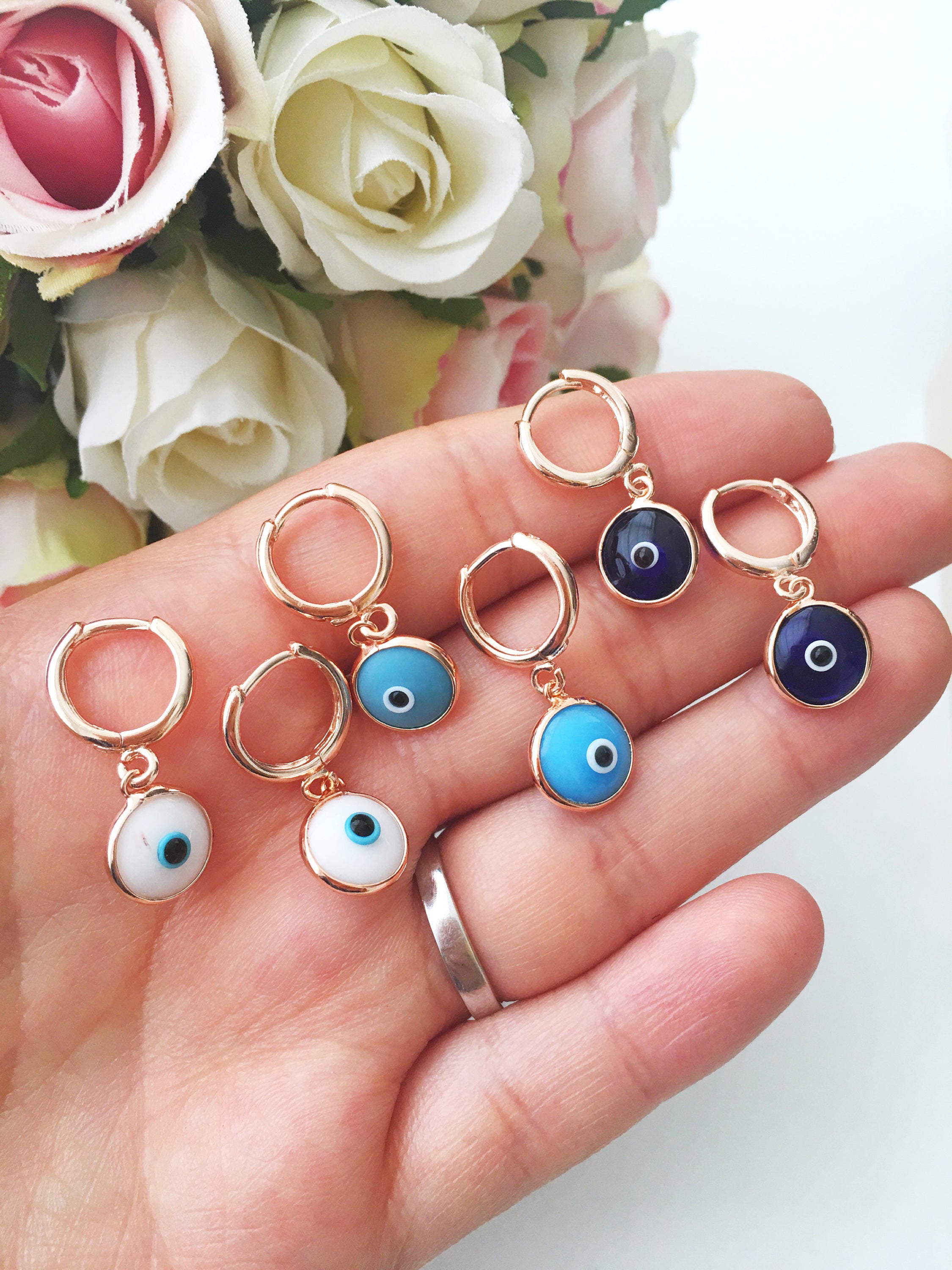 A pair of handmade turquoise hoop earrings featuring a glass evil eye bead, showcasing intricate craftsmanship and vibrant colors.