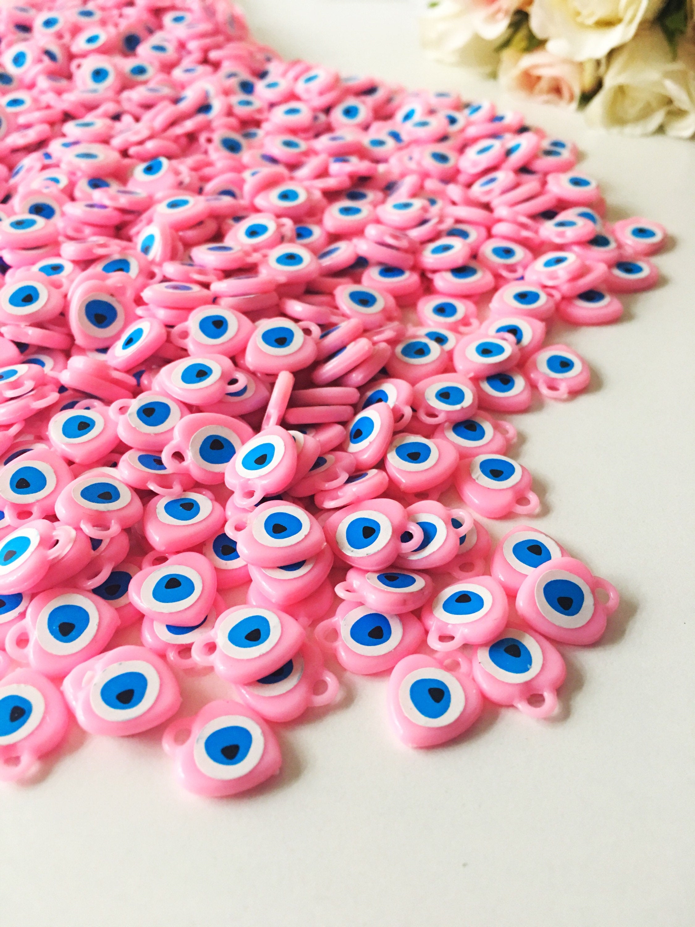 A collection of 100 unique evil eye wedding favors featuring plastic resin beads in dark blue and turquoise colors, symbolizing protection and luck.