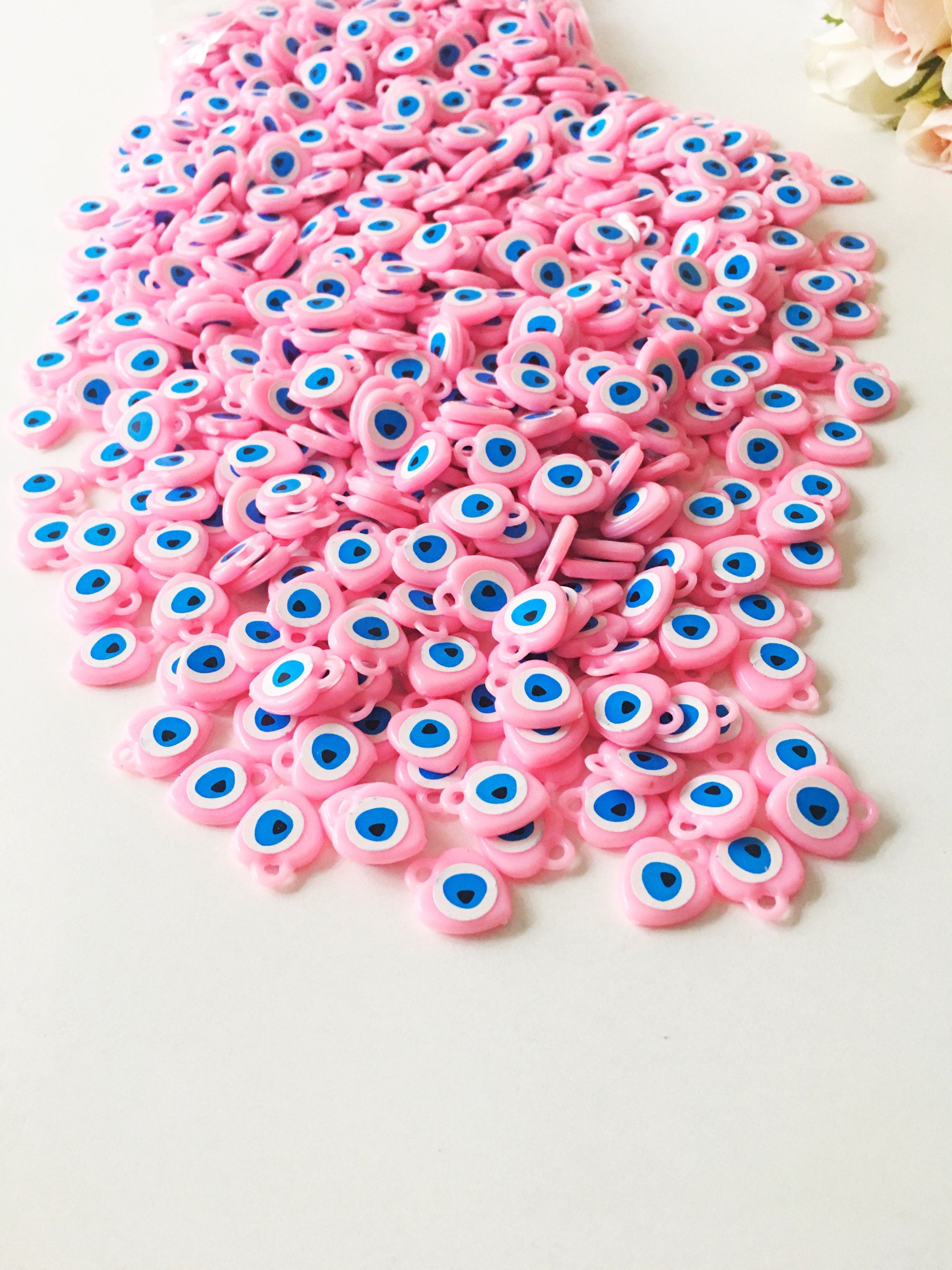 A collection of 100 unique evil eye wedding favors featuring plastic resin beads in dark blue and turquoise colors, symbolizing protection and luck.