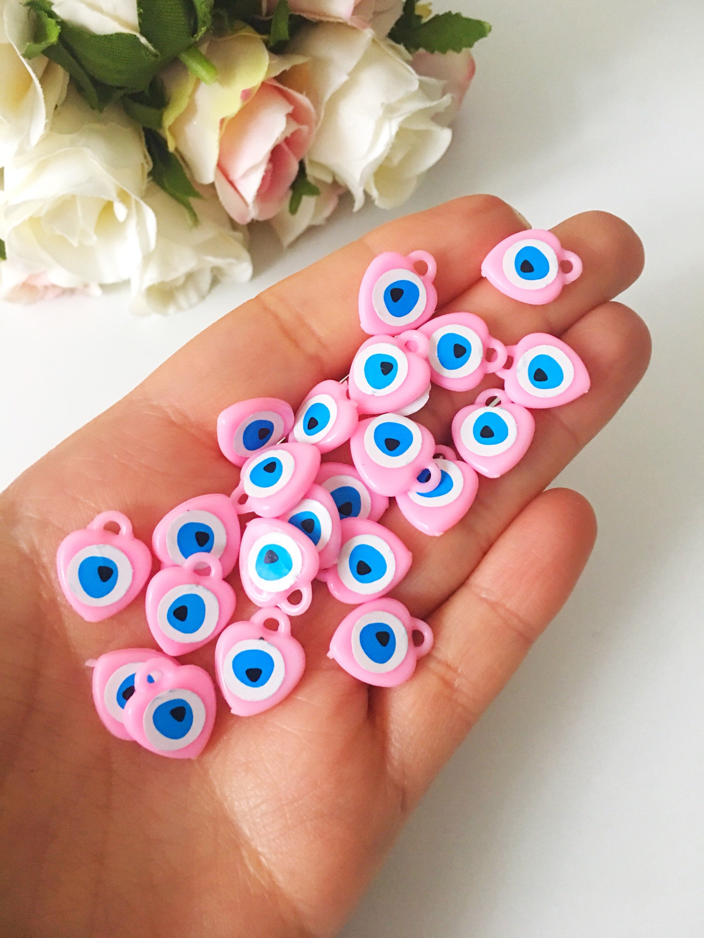 A collection of 100 unique evil eye wedding favors featuring plastic resin beads in dark blue and turquoise colors, symbolizing protection and luck.