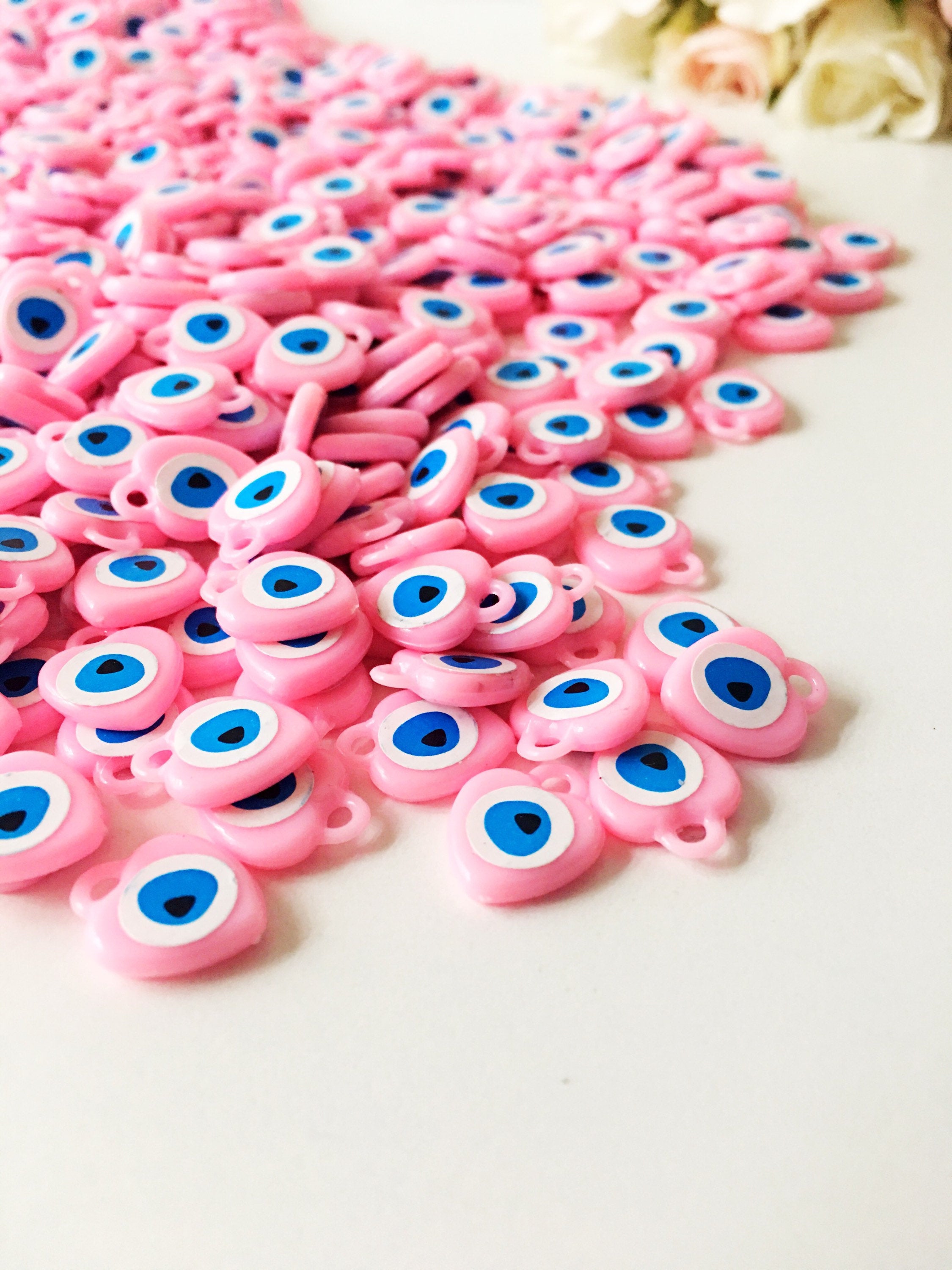 A collection of 100 unique evil eye wedding favors featuring plastic resin beads in dark blue and turquoise colors, symbolizing protection and luck.