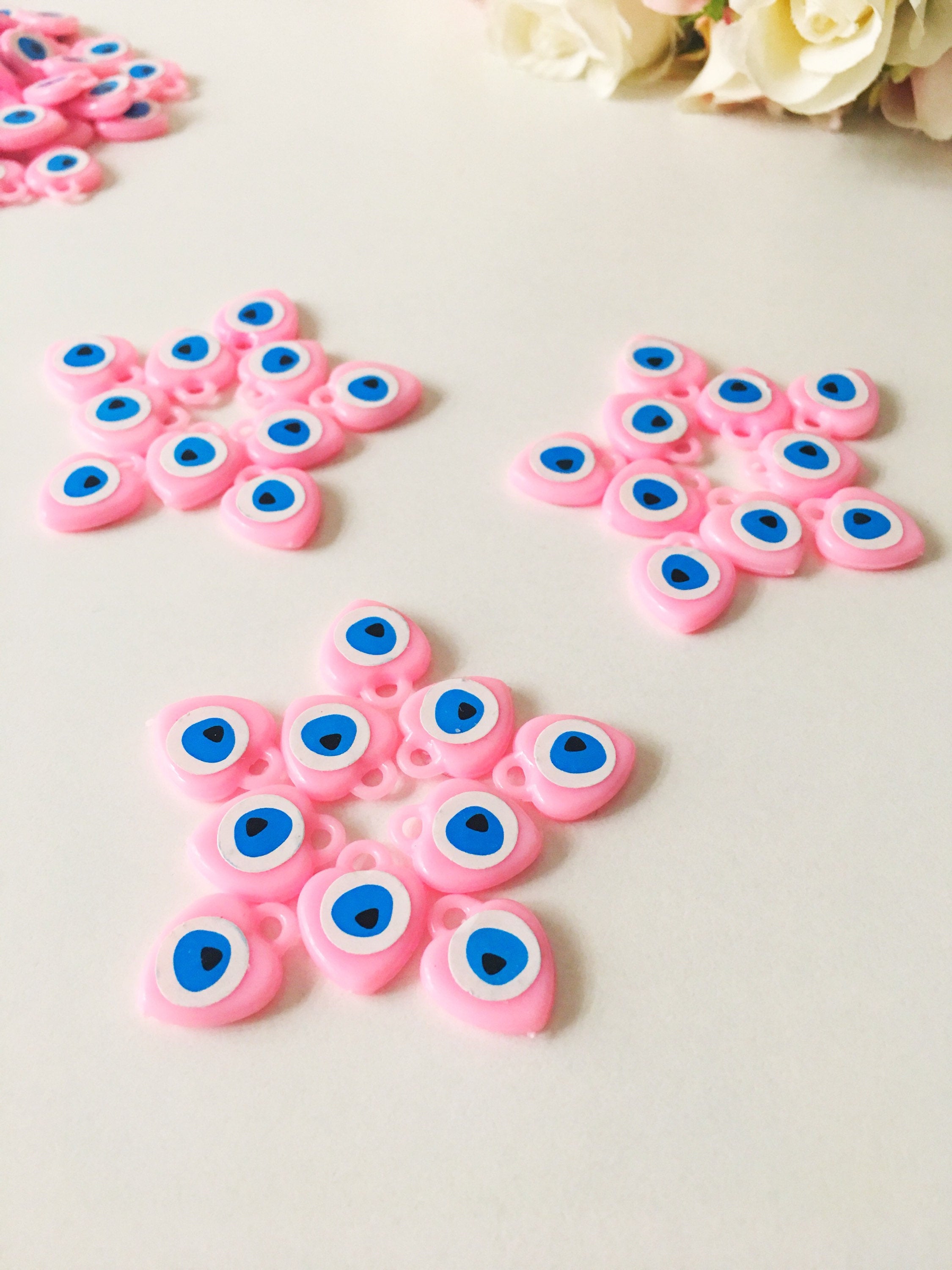 A collection of 100 unique evil eye wedding favors featuring plastic resin beads in dark blue and turquoise colors, symbolizing protection and luck.