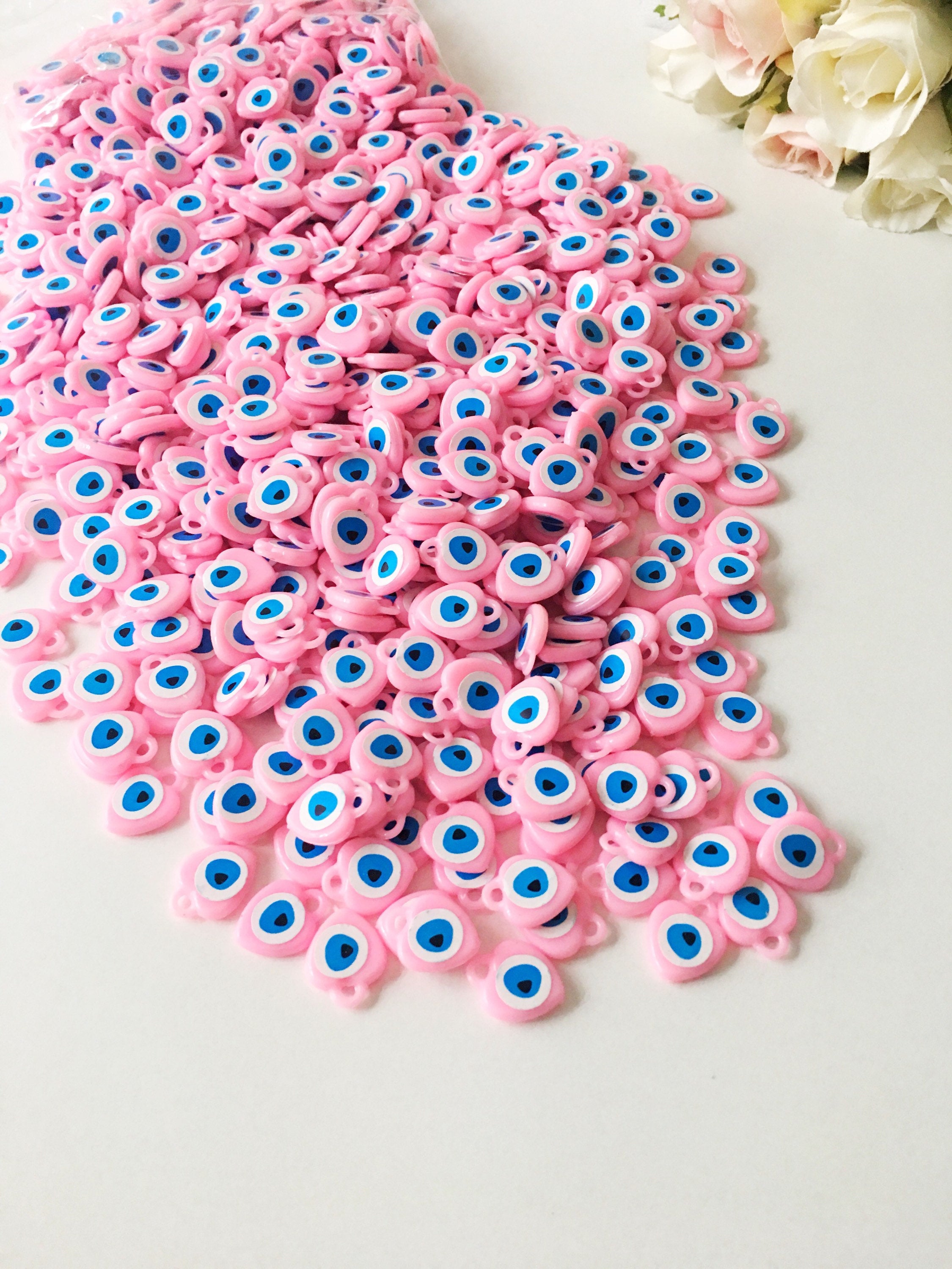 A collection of 100 unique evil eye wedding favors featuring plastic resin beads in dark blue and turquoise colors, symbolizing protection and luck.