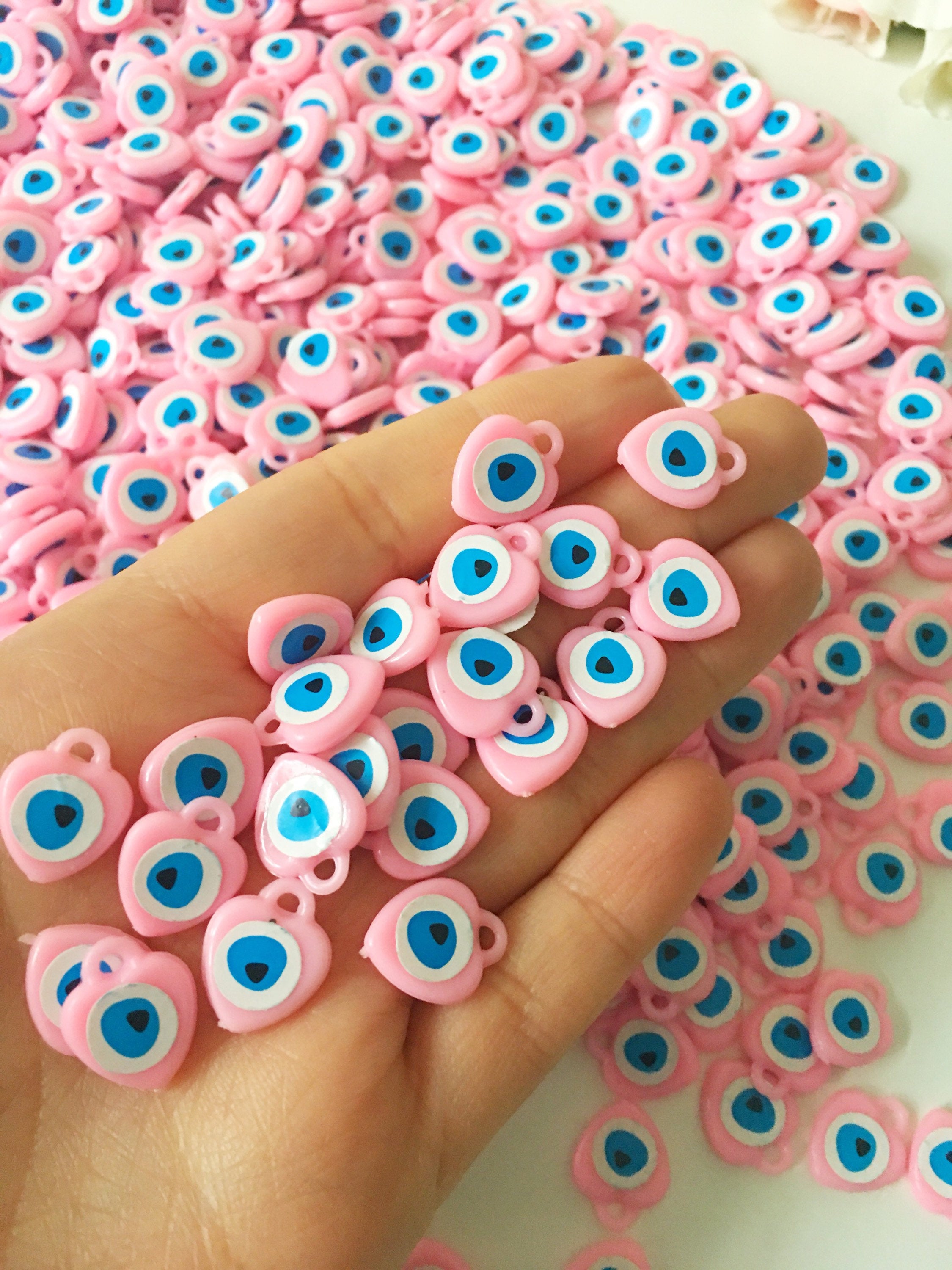 A collection of 100 unique evil eye wedding favors featuring plastic resin beads in dark blue and turquoise colors, symbolizing protection and luck.