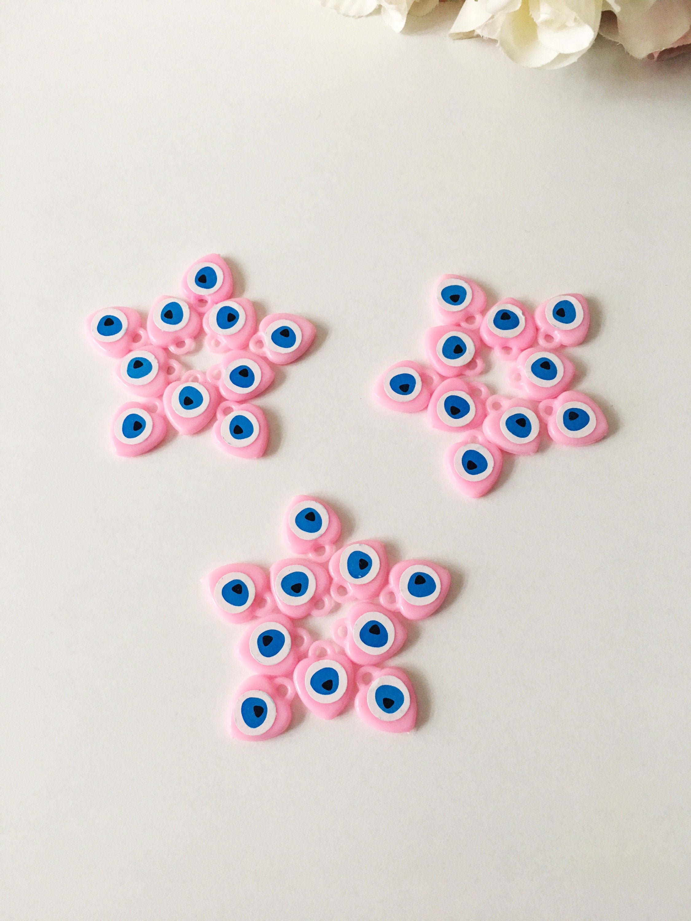 A collection of 100 unique evil eye wedding favors featuring plastic resin beads in dark blue and turquoise colors, symbolizing protection and luck.