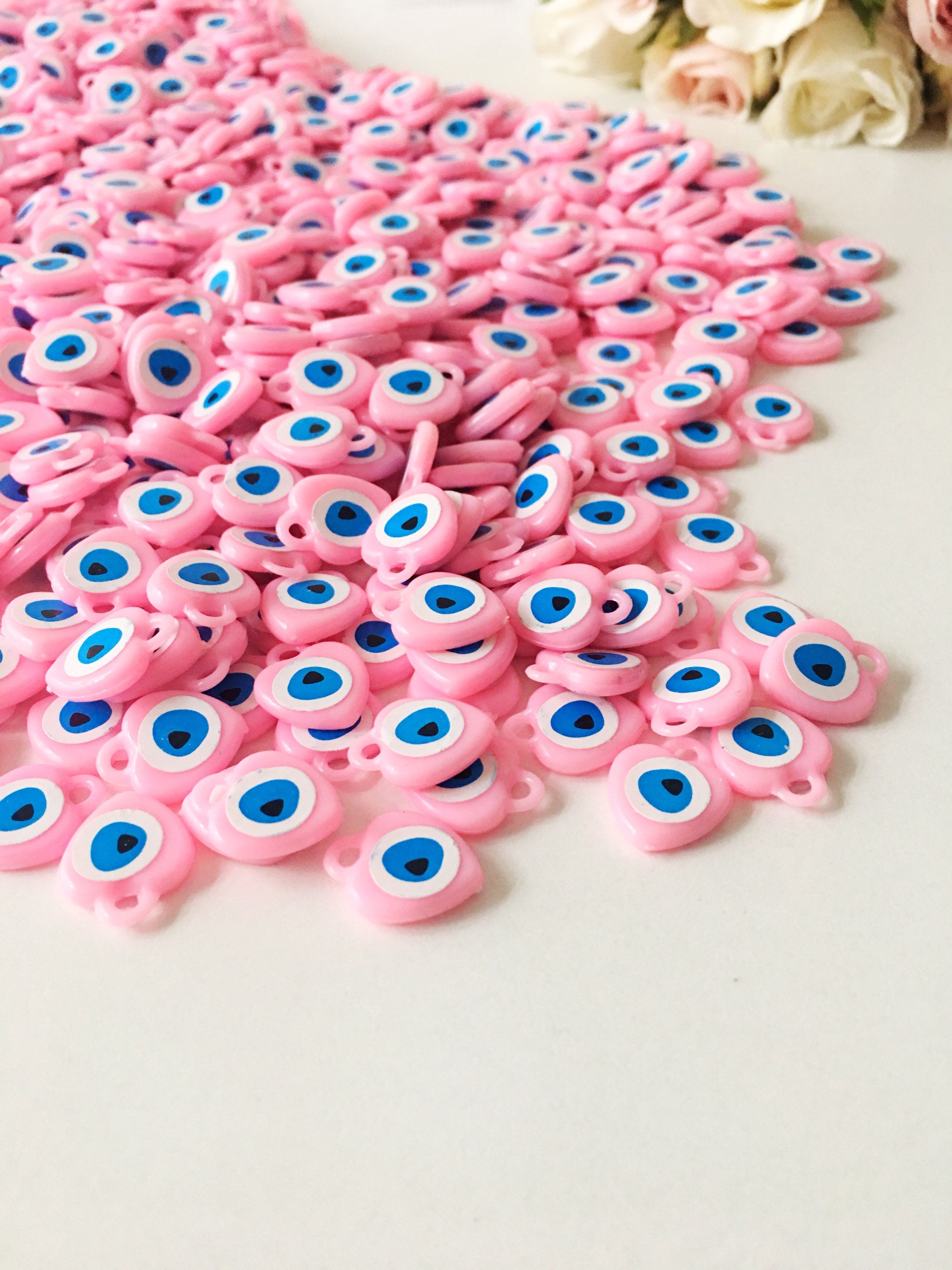 A collection of 100 unique evil eye wedding favors featuring plastic resin beads in dark blue and turquoise colors, symbolizing protection and luck.