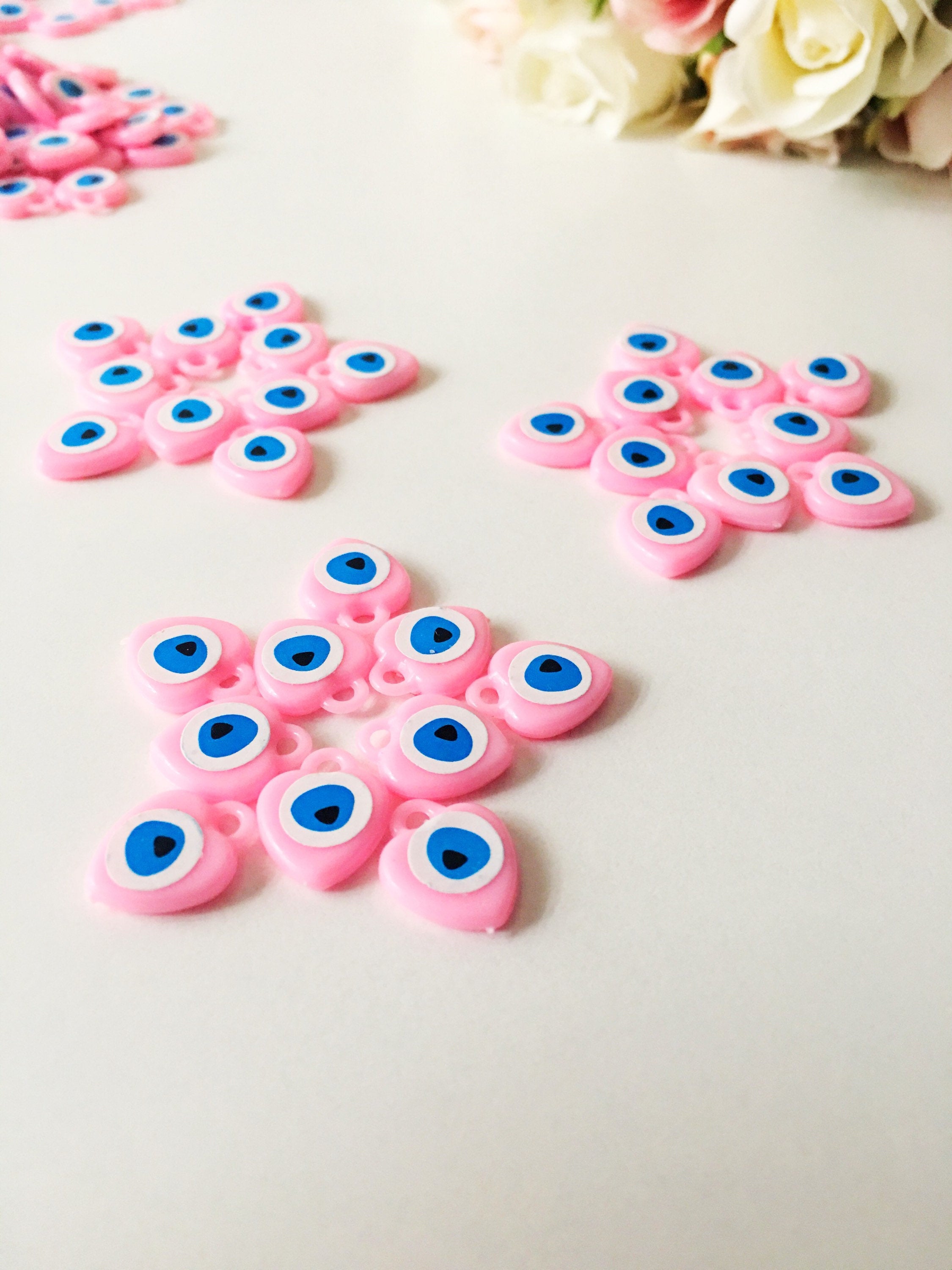 A collection of 100 unique evil eye wedding favors featuring plastic resin beads in dark blue and turquoise colors, symbolizing protection and luck.