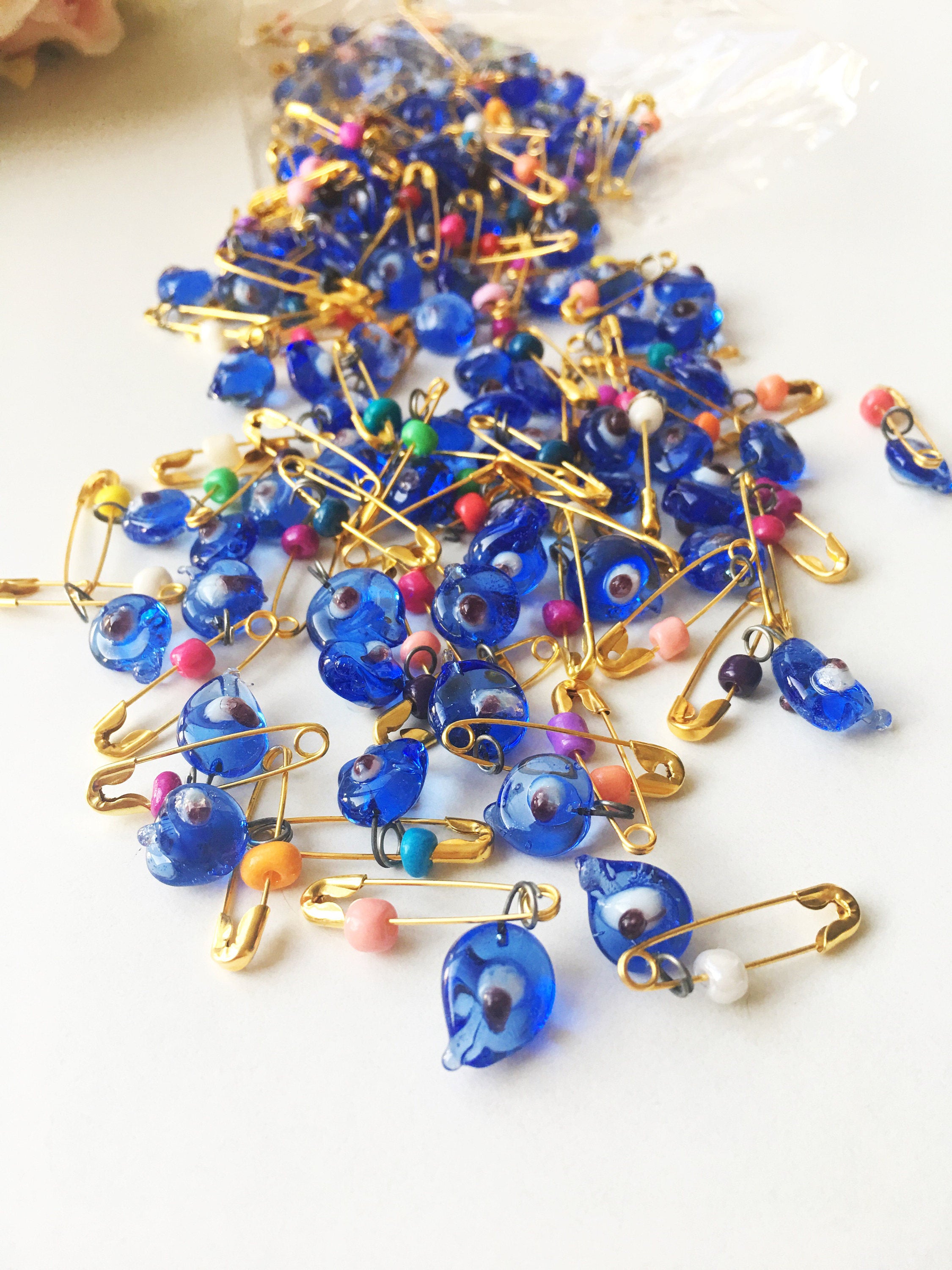 A collection of unique evil eye safety pins adorned with colorful Miyuki beads, perfect for wedding favors and baby showers.