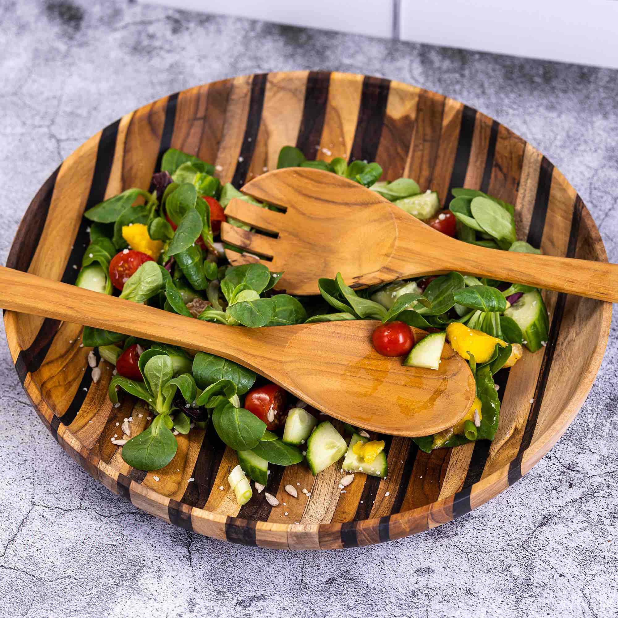 Upcycled eco-friendly wooden salad servers made from reclaimed teak wood, showcasing unique grain patterns and a polished finish.