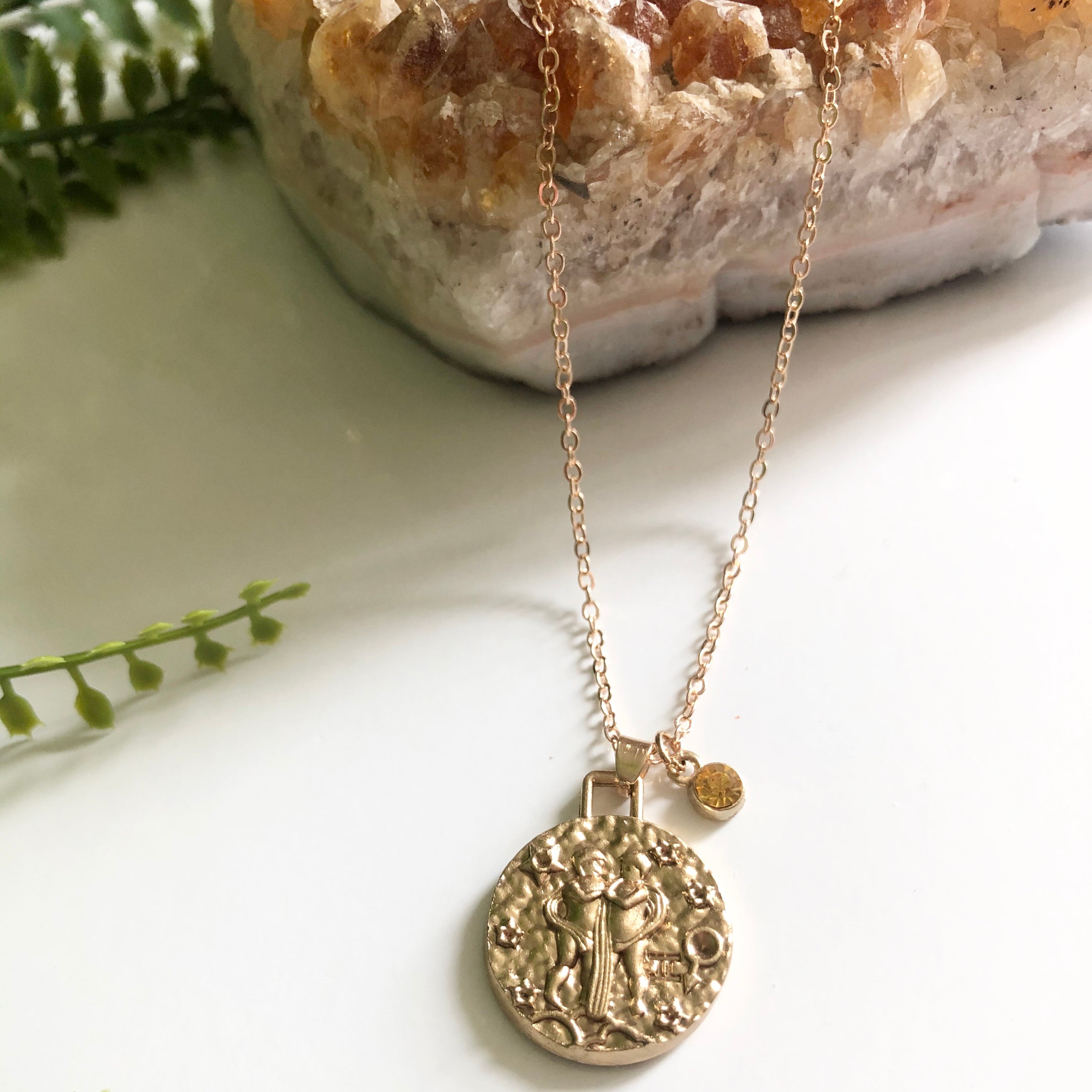 A beautiful 24K gold plated zodiac necklace featuring a double-sided pendant with astrological sign on one side and zodiac sign stamped on the other.