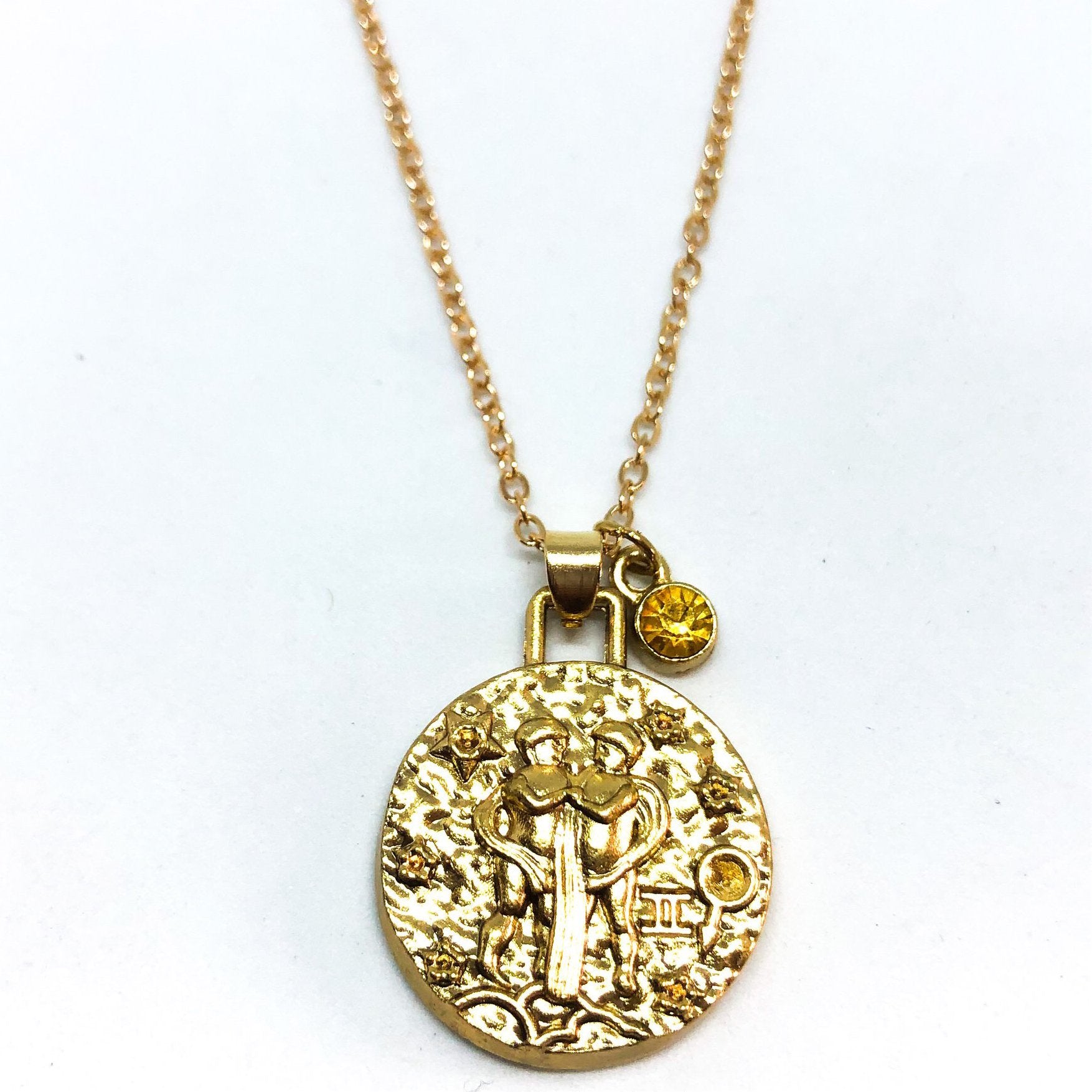 A beautiful 24K gold plated zodiac necklace featuring a double-sided pendant with astrological sign on one side and zodiac sign stamped on the other.