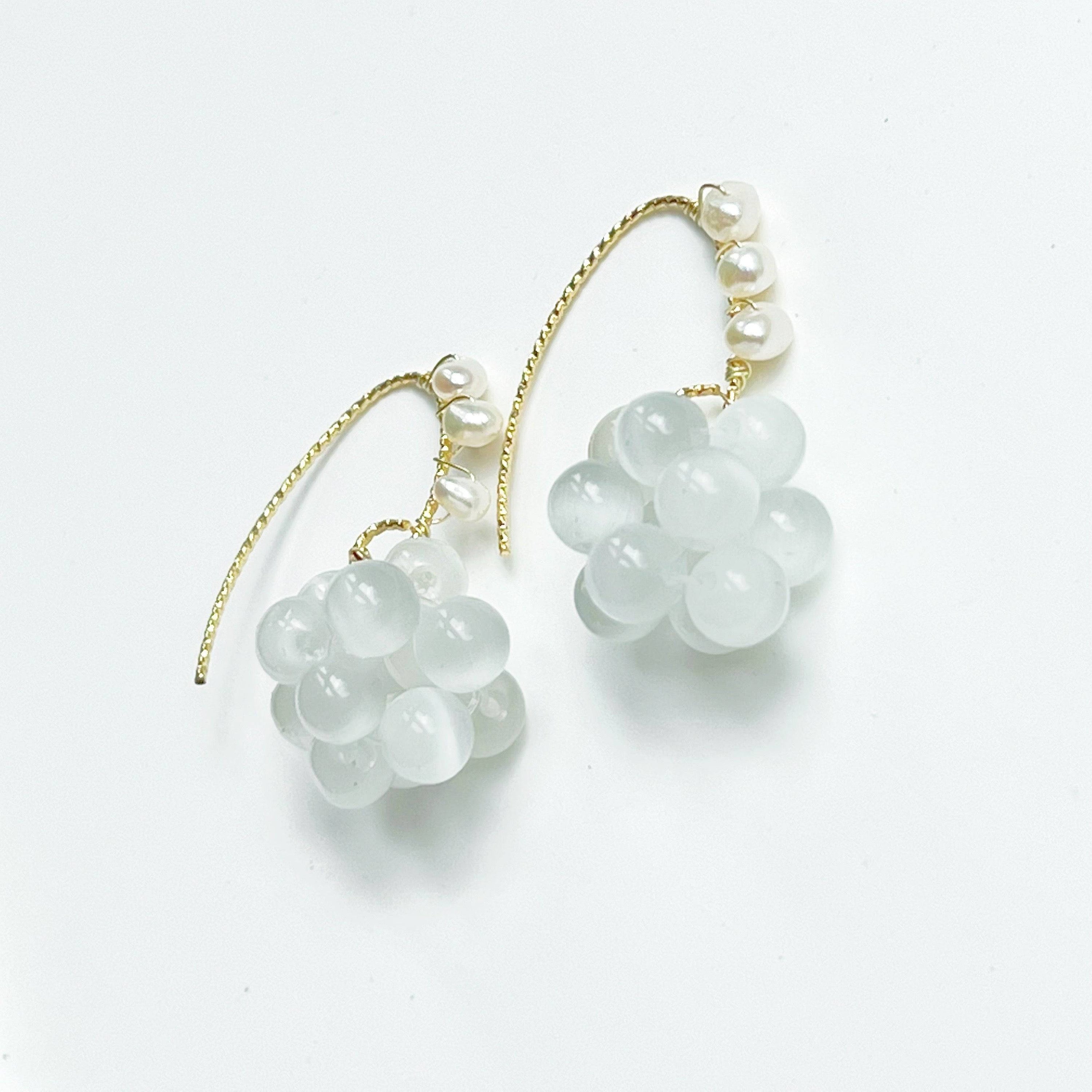 Elegant drop earrings featuring white cat's eye stone beads and pearls, with gold-plated bronze ear wire.