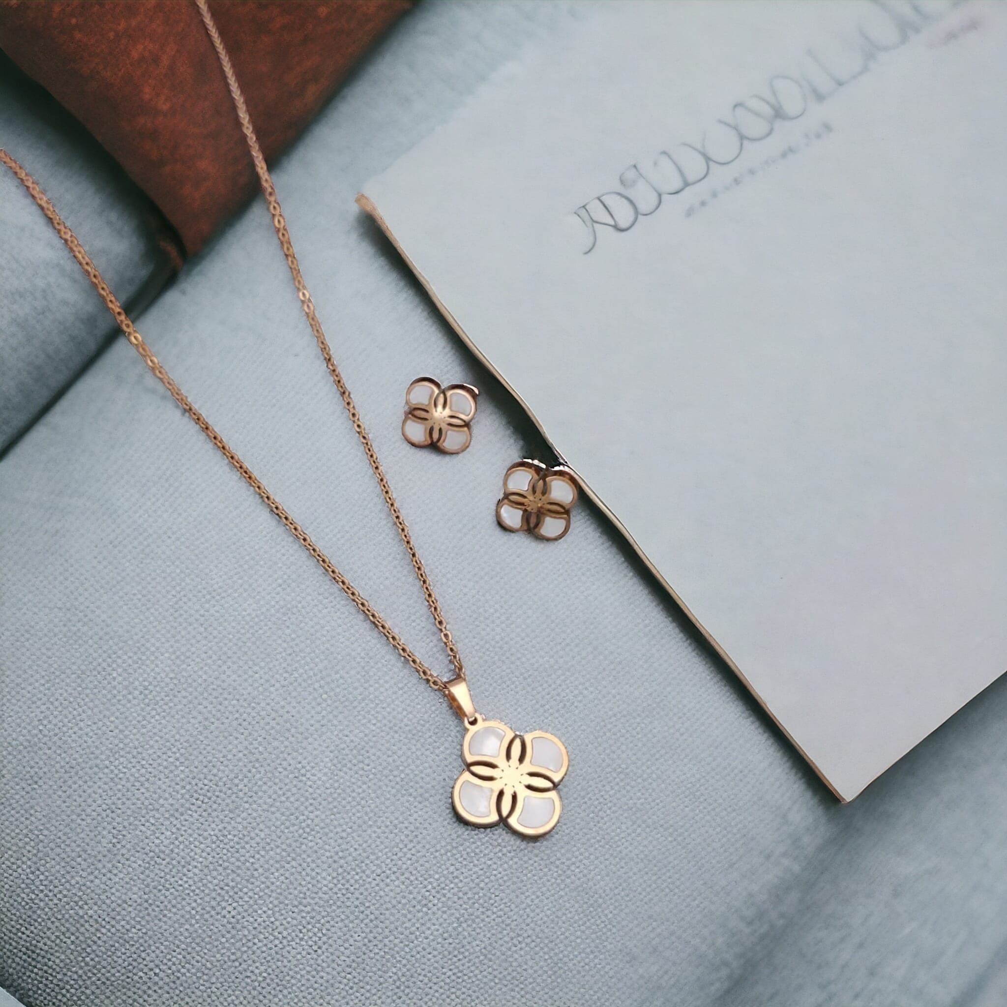 White Enamel Minimalistic Clover Pendant Necklace and Earring Set featuring a rotating clover pendant, crafted from 18ct gold-plated material.