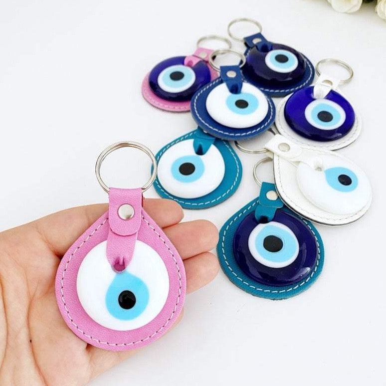 White Evil Eye Bead Leather Keychain featuring a blue and pink evil eye bead, stylishly designed for protection and elegance.