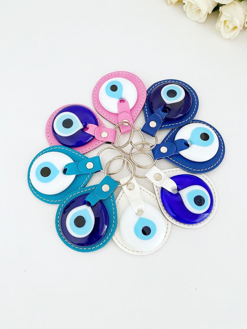 White Evil Eye Bead Leather Keychain featuring a blue and pink evil eye bead, stylishly designed for protection and elegance.