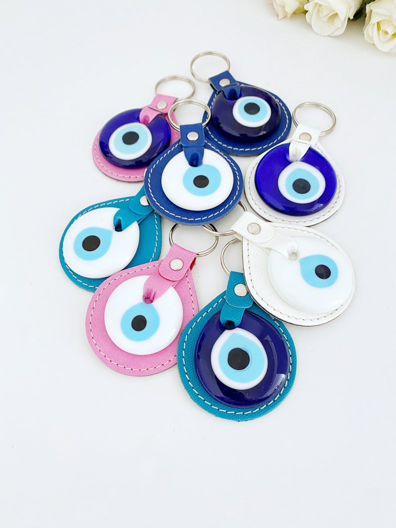 White Evil Eye Bead Leather Keychain featuring a blue and pink evil eye bead, stylishly designed for protection and elegance.