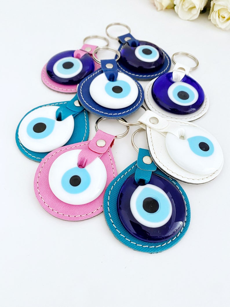 White Evil Eye Bead Leather Keychain featuring a blue and pink evil eye bead, stylishly designed for protection and elegance.