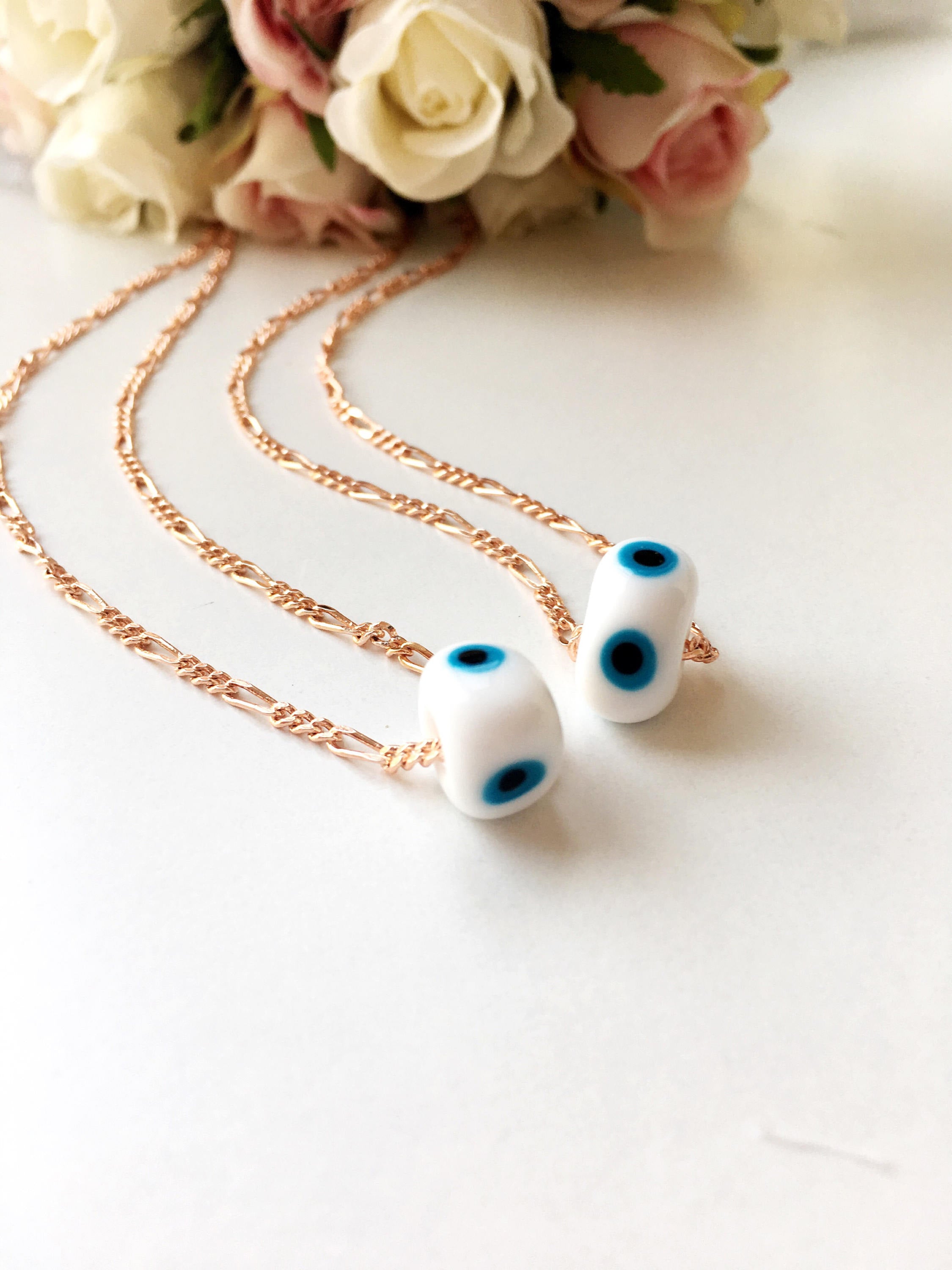 Handmade white evil eye necklace featuring Murano glass beads and a rose gold stainless steel chain, symbolizing protection and style.