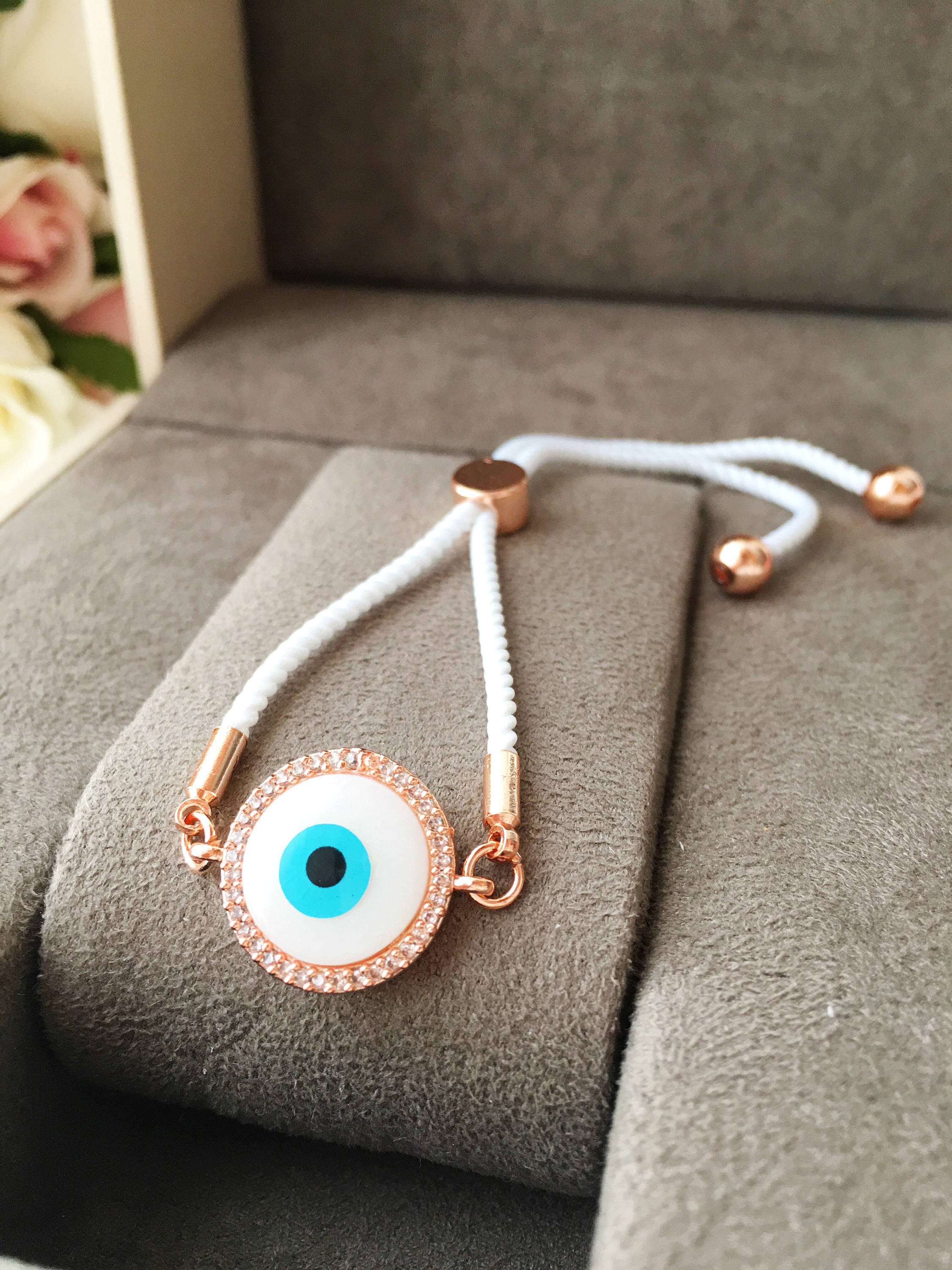 A beautifully crafted White Evil Eye Bracelet featuring a mother of pearl centerpiece, adjustable white string, and zirconia accents.