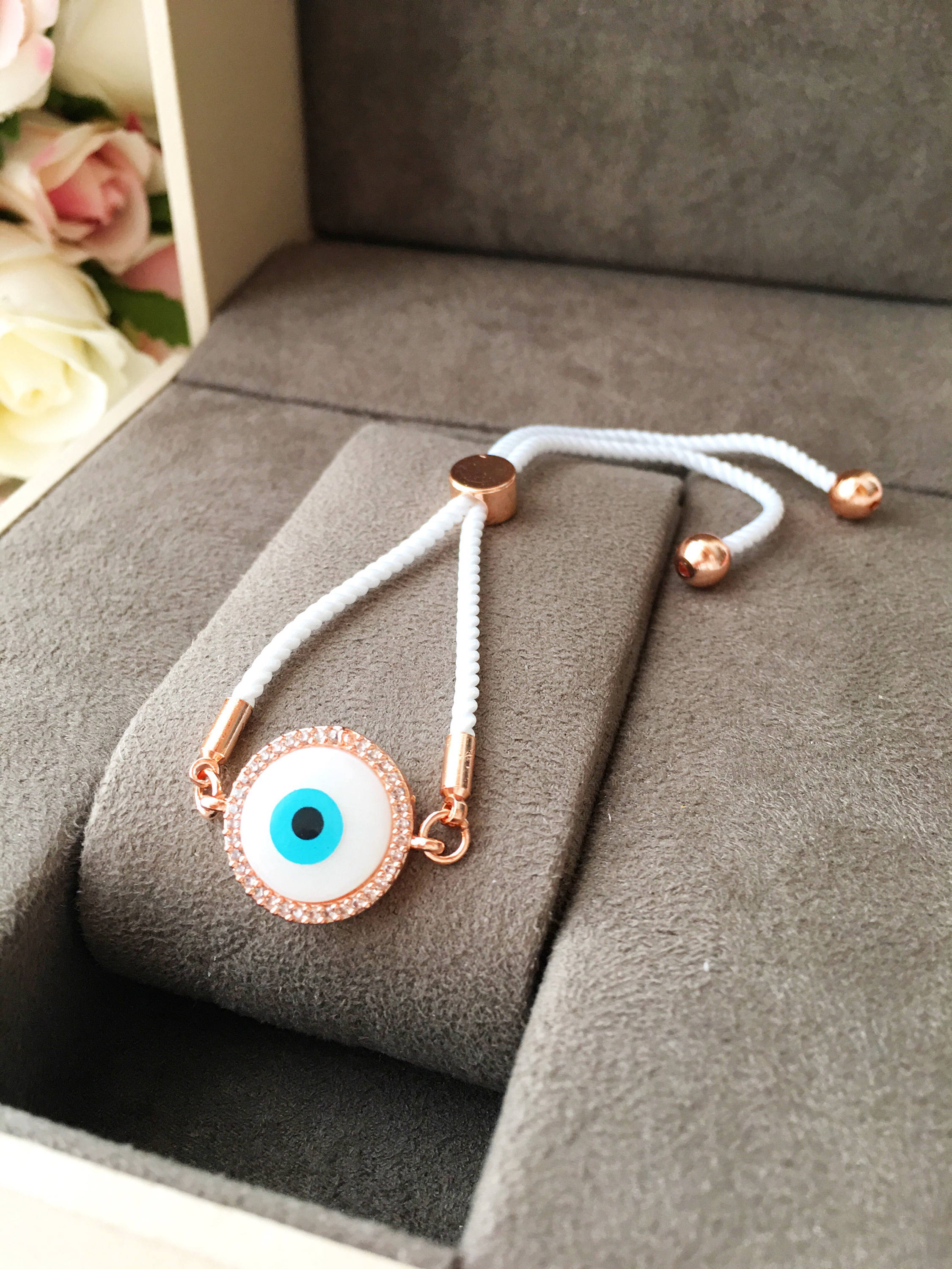 A beautifully crafted White Evil Eye Bracelet featuring a mother of pearl centerpiece, adjustable white string, and zirconia accents.