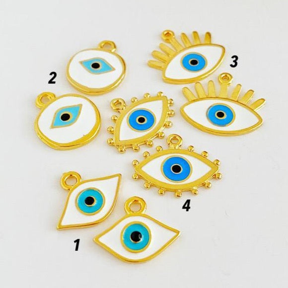 A collection of White Evil Eye Charms in various styles, showcasing their brass material and intricate designs.