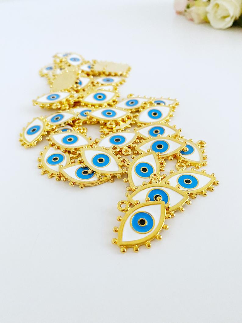A beautiful White Evil Eye Charm featuring an enamel bead design with a gold evil eye pendant, perfect for jewelry making.