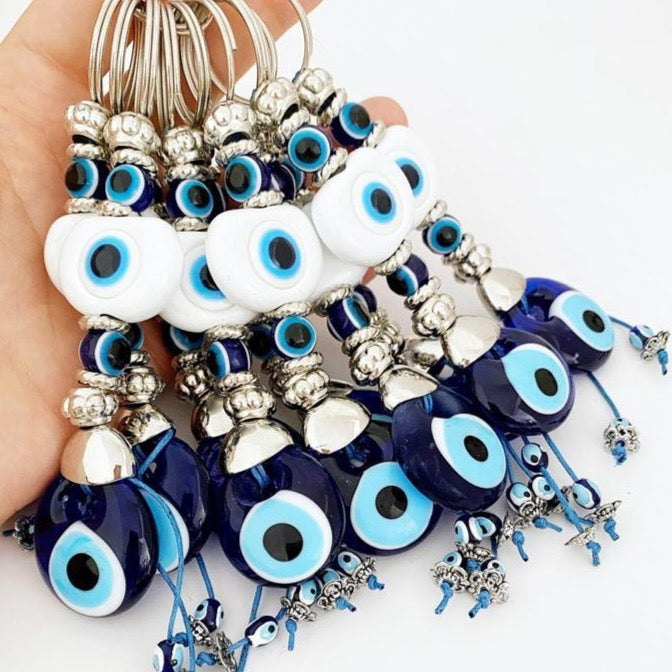A beautiful White Evil Eye Keychain featuring a white oval bead and a blue evil eye bead, symbolizing protection and good luck.