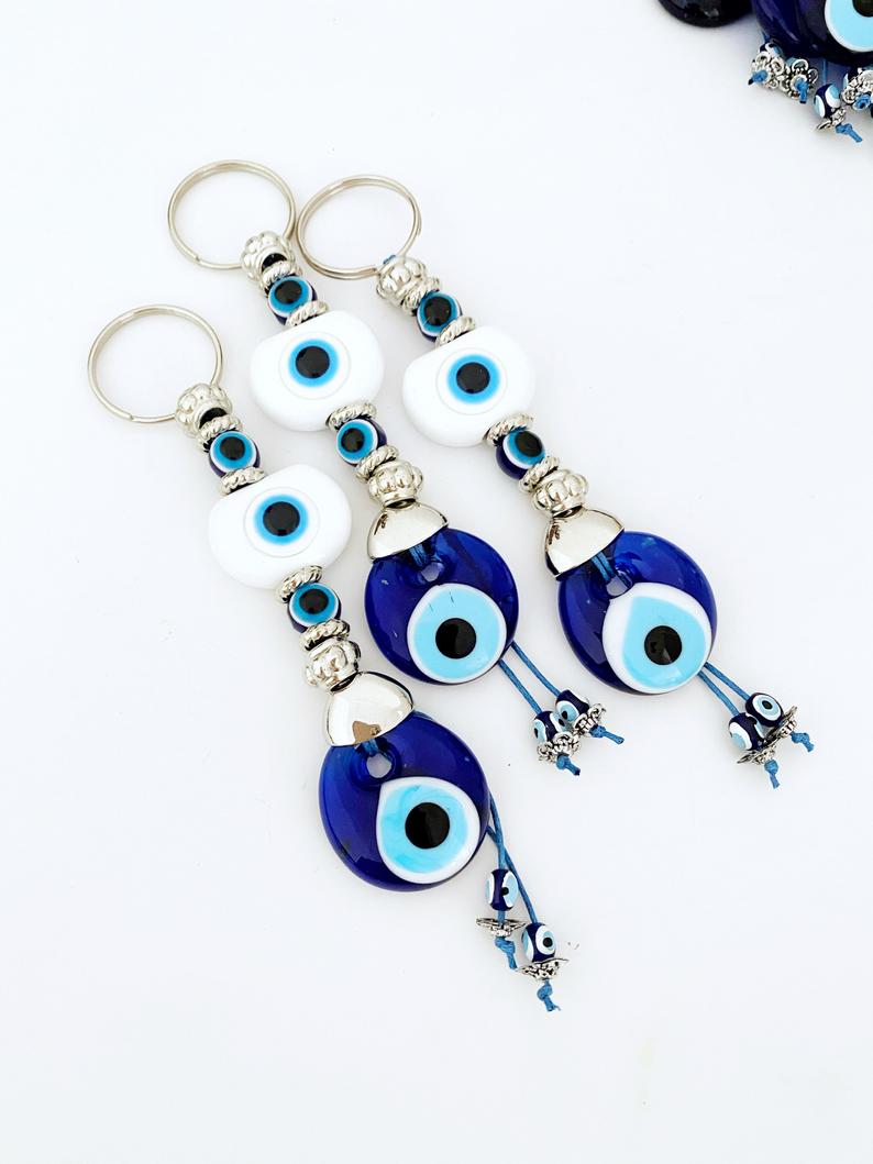 A beautiful White Evil Eye Keychain featuring a white oval bead and a blue evil eye bead, symbolizing protection and good luck.