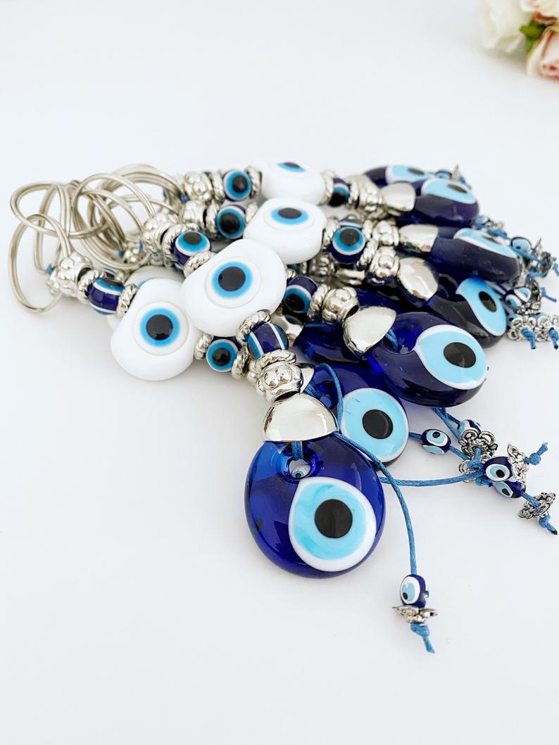 A beautiful White Evil Eye Keychain featuring a white oval bead and a blue evil eye bead, symbolizing protection and good luck.