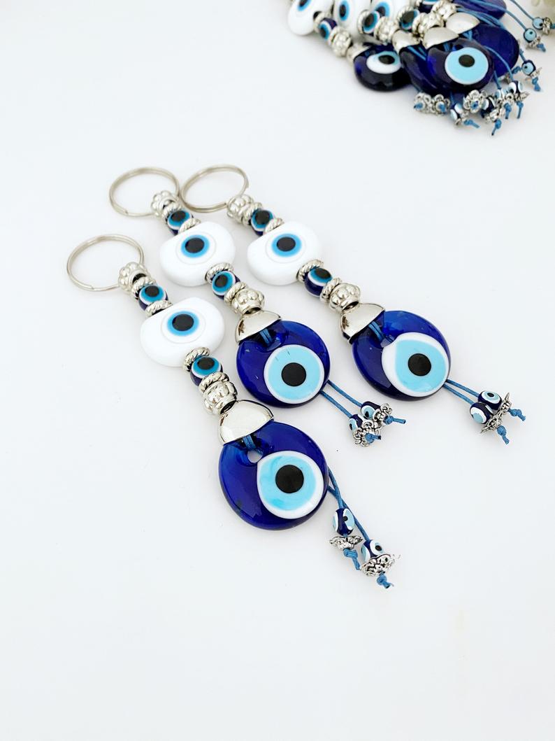 A beautiful White Evil Eye Keychain featuring a white oval bead and a blue evil eye bead, symbolizing protection and good luck.