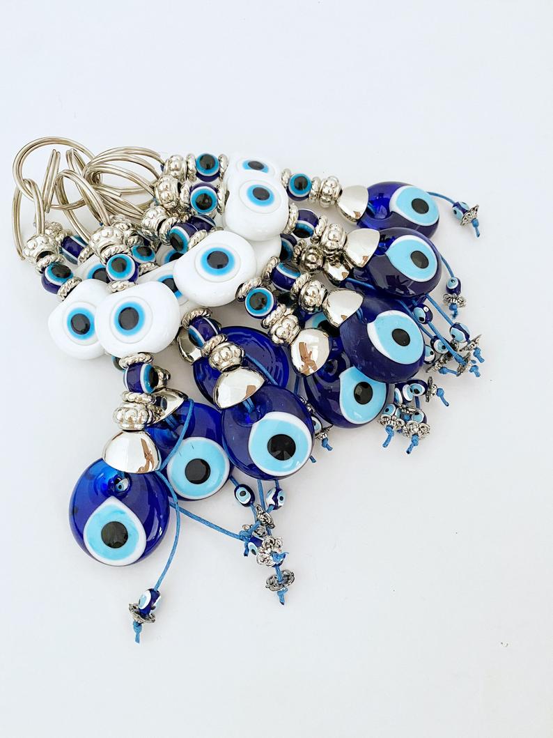 A beautiful White Evil Eye Keychain featuring a white oval bead and a blue evil eye bead, symbolizing protection and good luck.