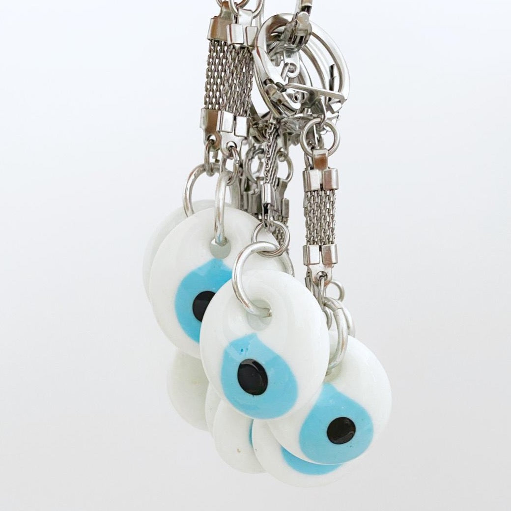 A beautiful white evil eye keychain featuring glass beads and a silver keyring, symbolizing protection and good luck.
