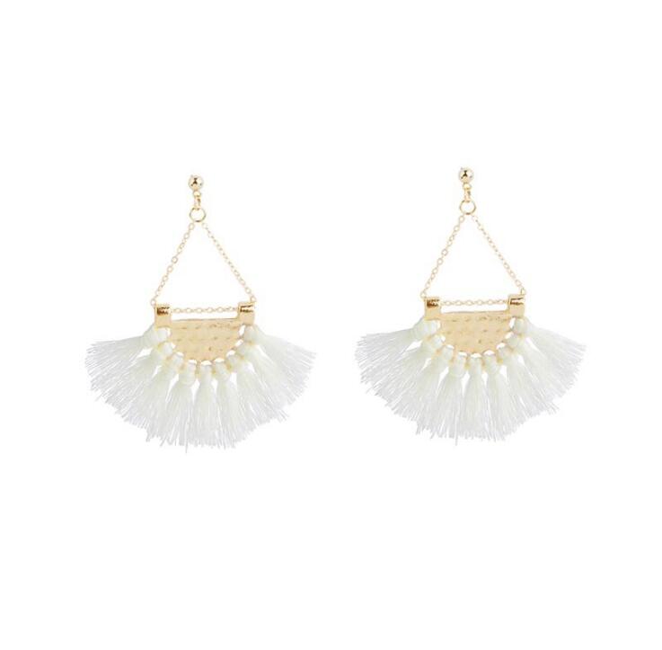 Elegant white tassel earrings hanging from a hammered-metal hoop, showcasing their stylish design and lightweight appeal.