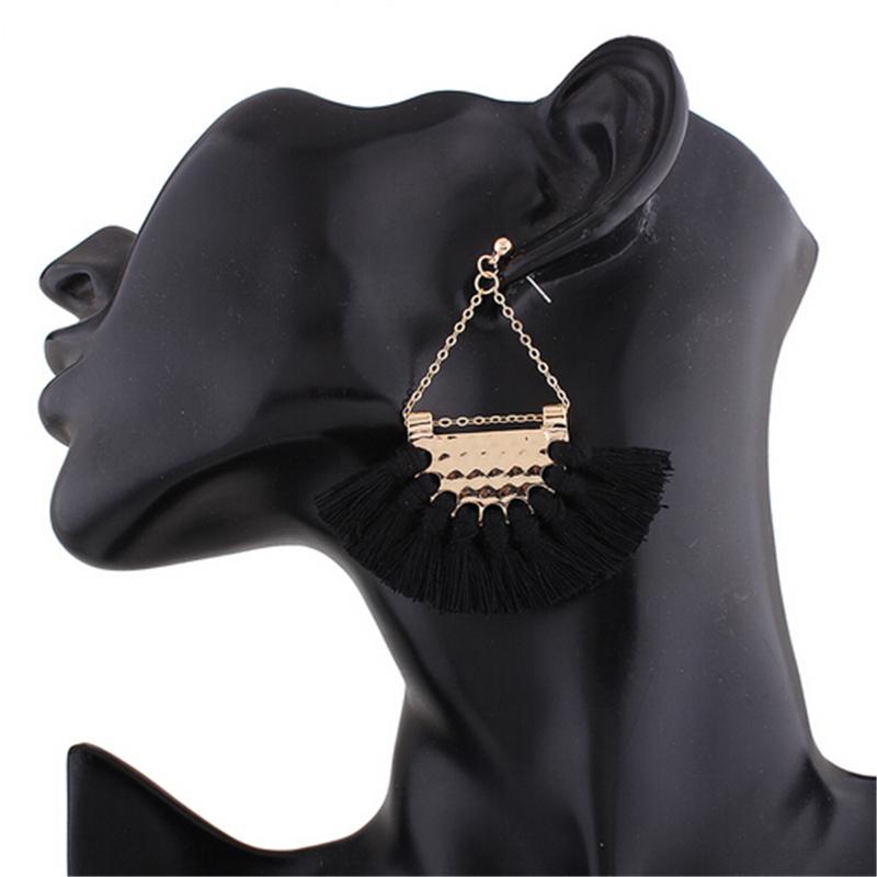 Elegant white tassel earrings hanging from a hammered-metal hoop, showcasing their stylish design and lightweight appeal.