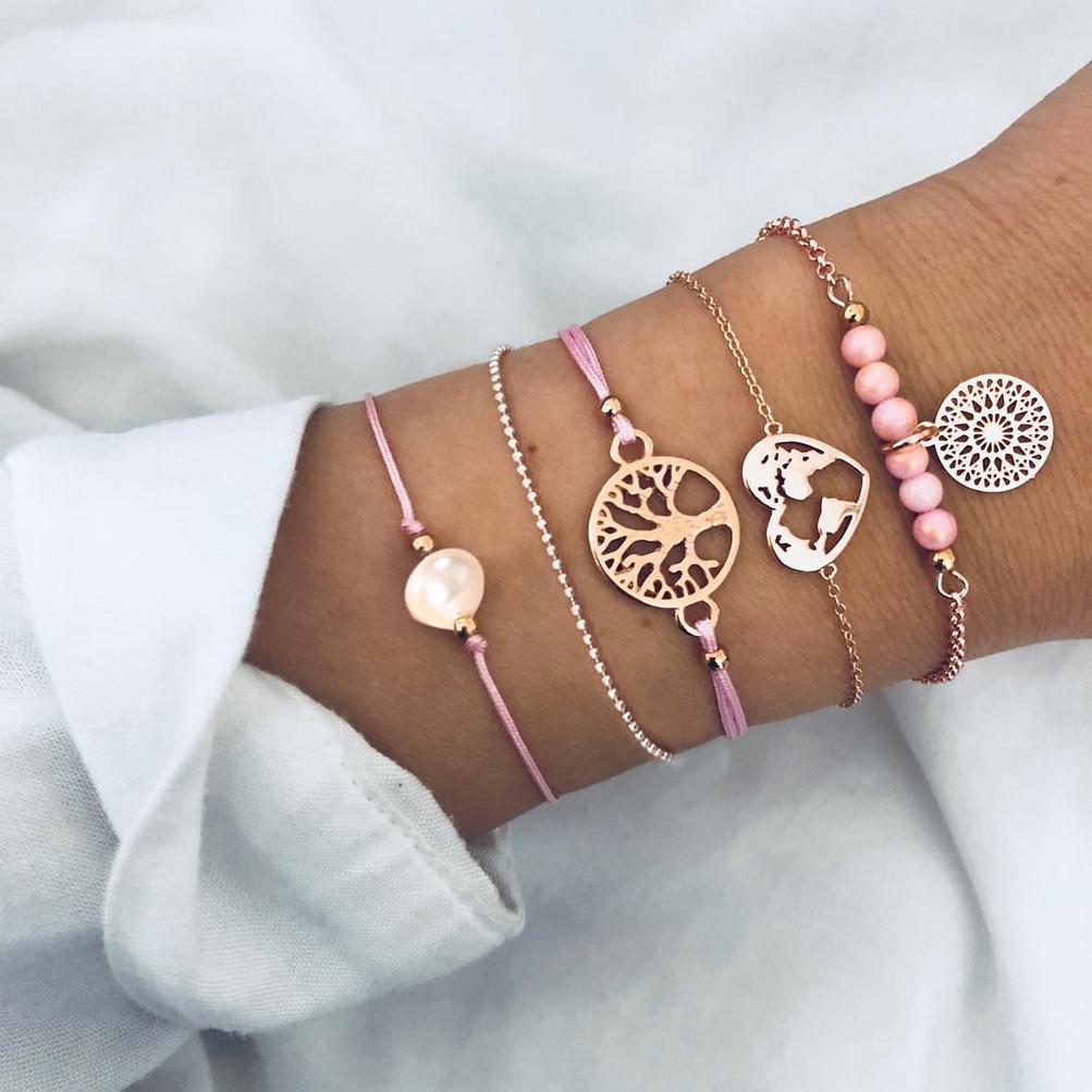 Women of The World Unite 5 Piece Bracelet Set featuring 14K gold plating, pink marble, filigree world pendant, and Tree of Life pendant.