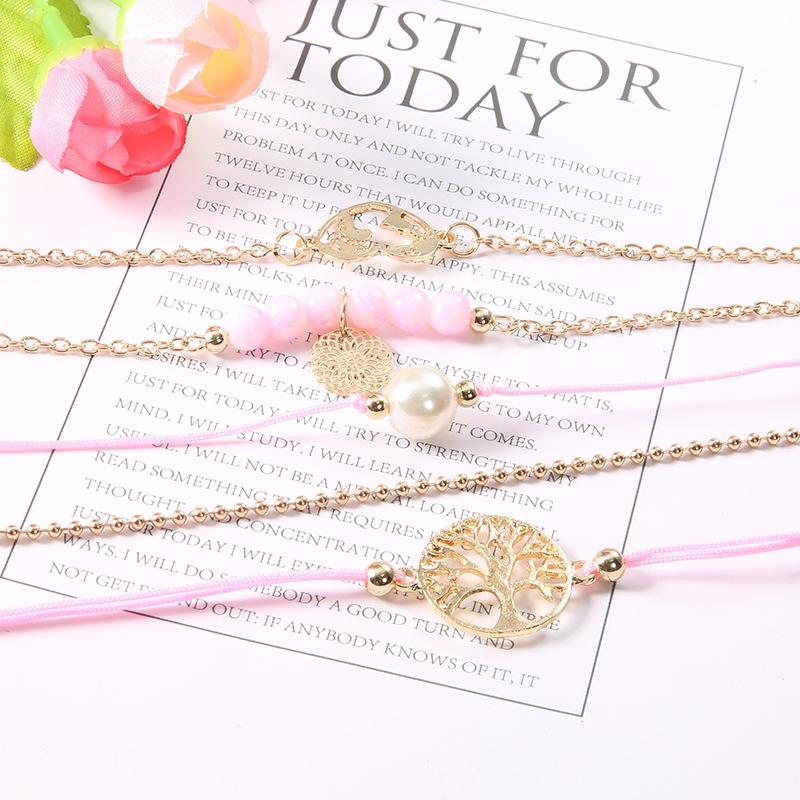 Women of The World Unite 5 Piece Bracelet Set featuring 14K gold plating, pink marble, filigree world pendant, and Tree of Life pendant.