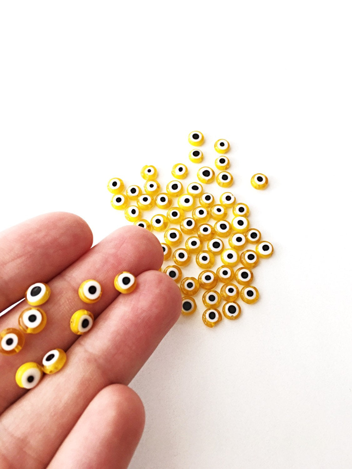 A collection of yellow evil eye beads in various sizes, showcasing their vibrant color and unique handmade designs.