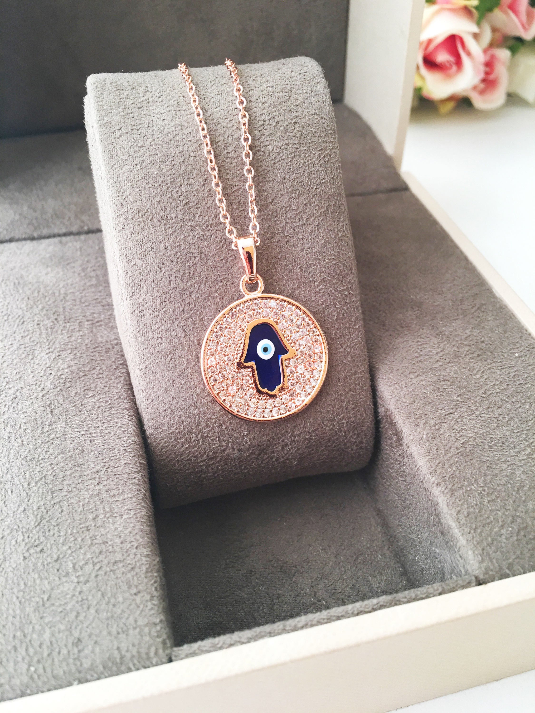 Zircon Evil Eye Necklace featuring a Hamsa Hand charm, available in gold and rose gold, showcasing intricate handmade craftsmanship.