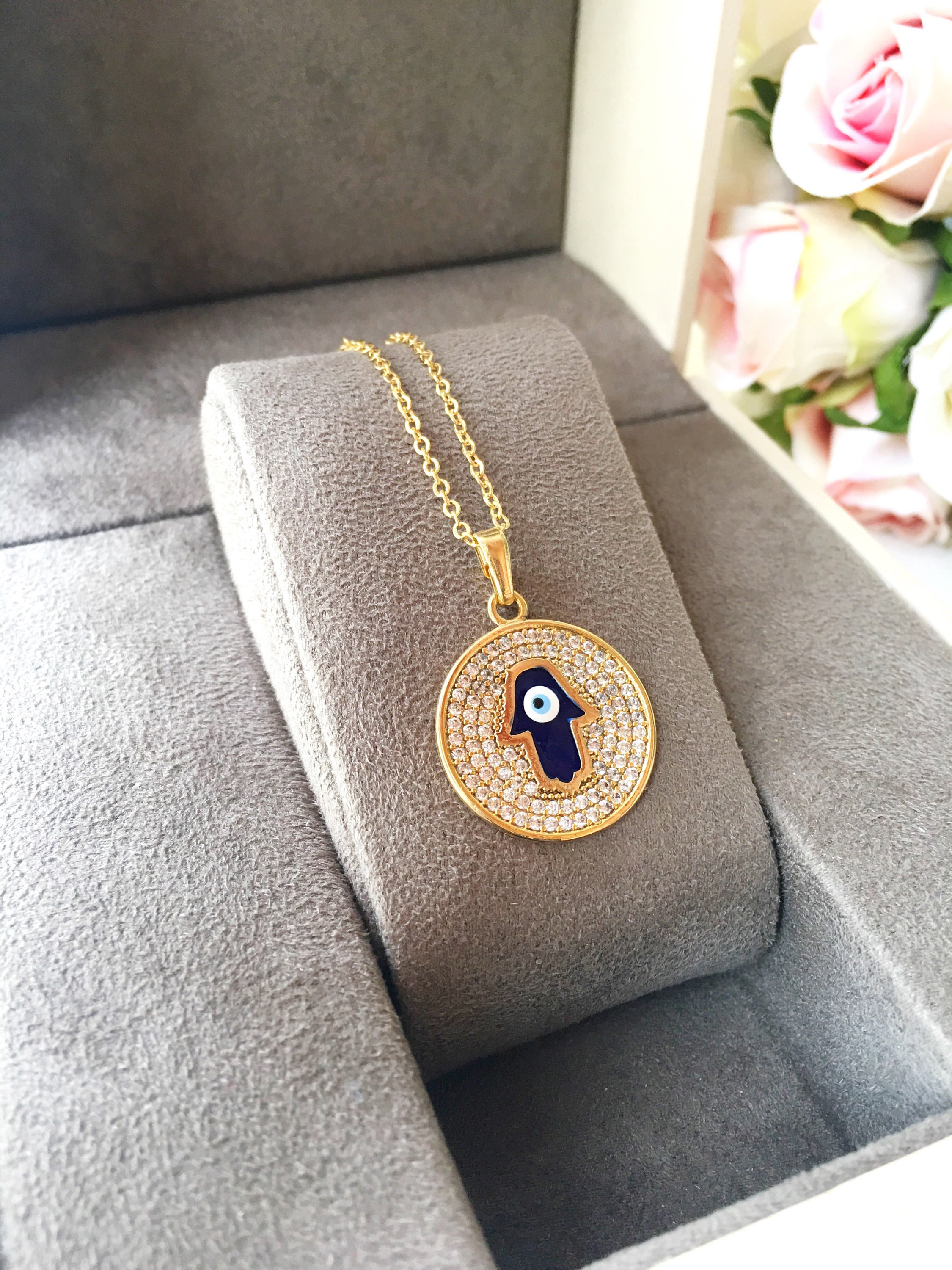 Zircon Evil Eye Necklace featuring a Hamsa Hand charm, available in gold and rose gold, showcasing intricate handmade craftsmanship.