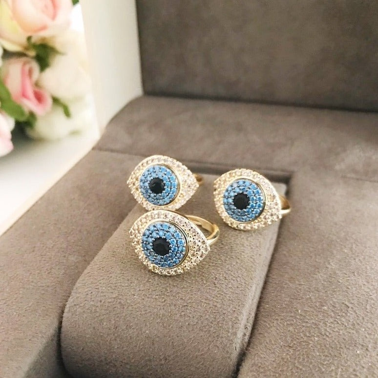 A stunning Zirconia Evil Eye Ring featuring a blue evil eye bead and sparkling zirconia stones, set in a gold adjustable band.